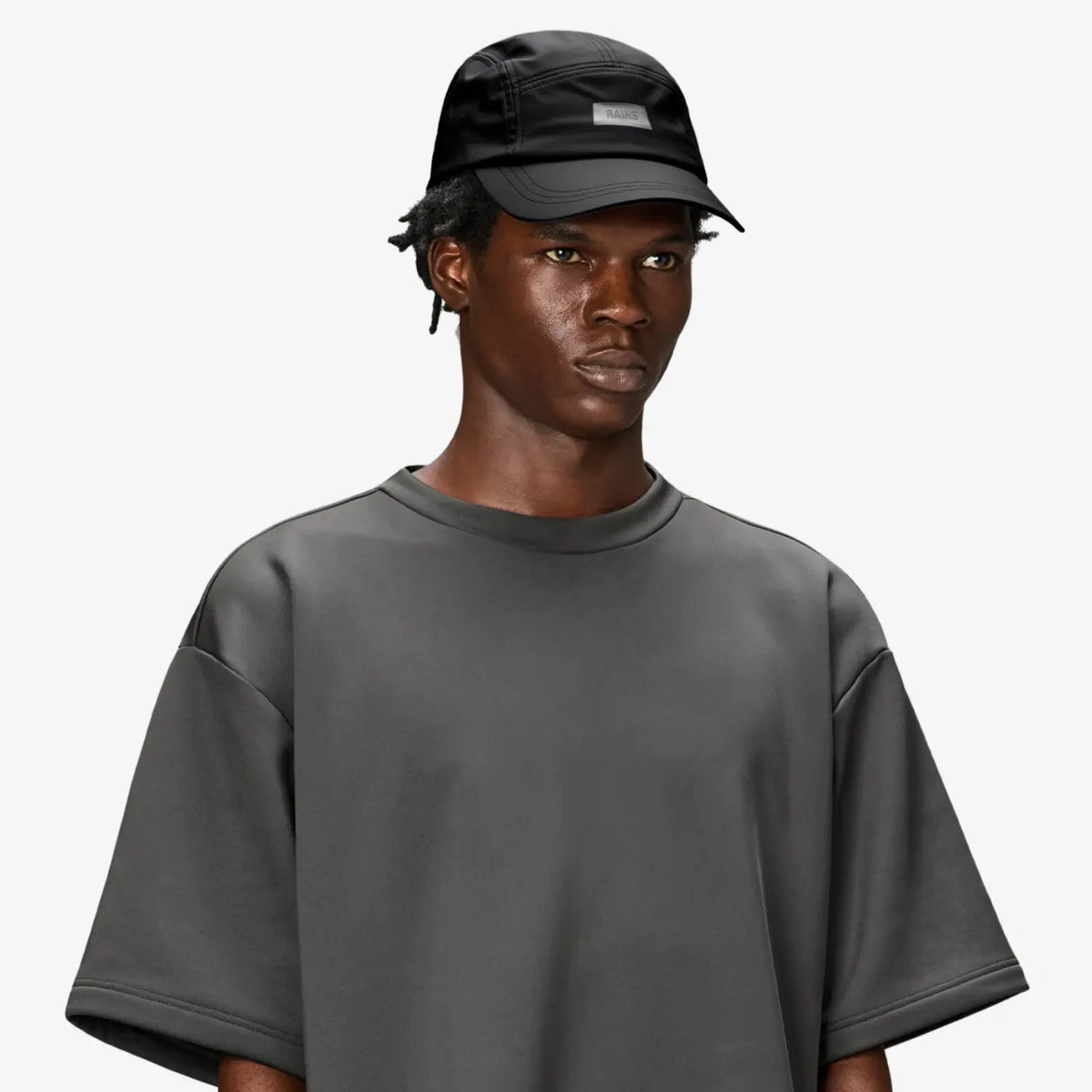 5 Panel Cap noire portée, calotte souple et étiquette grise sur le panneau avant