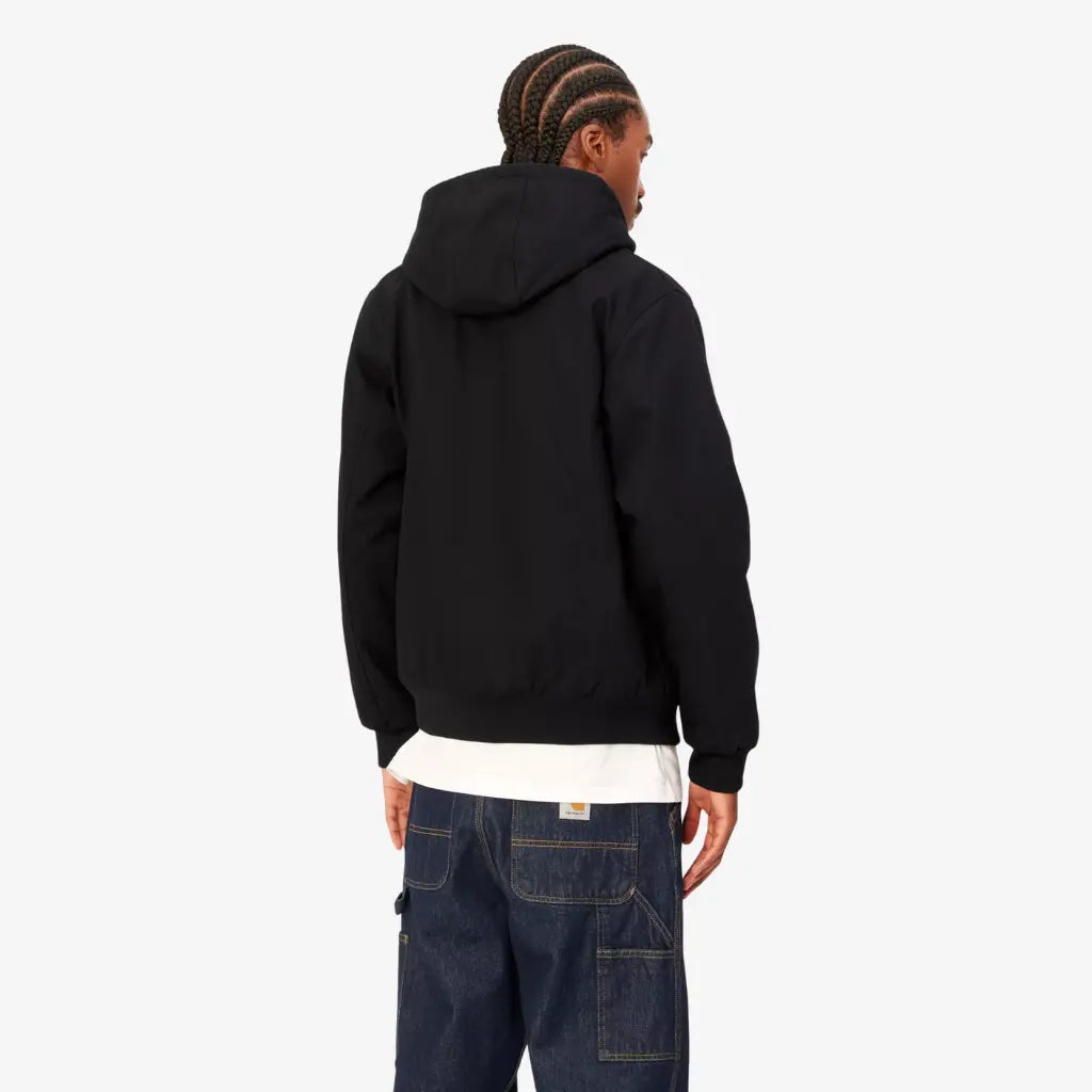Veste Active Winter Black Rigid Carhartt WIP portée de dos, capuche rabattue et ourlet côtelé