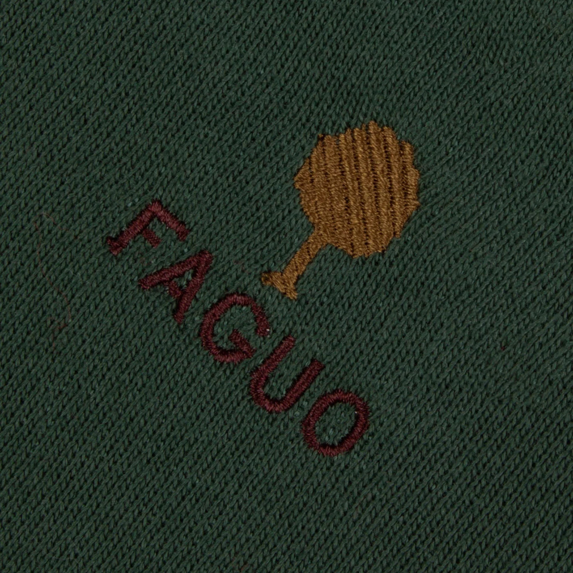 Gros plan de la broderie arbre ocre et du lettrage FAGUO bordeaux sur le molleton vert forêt