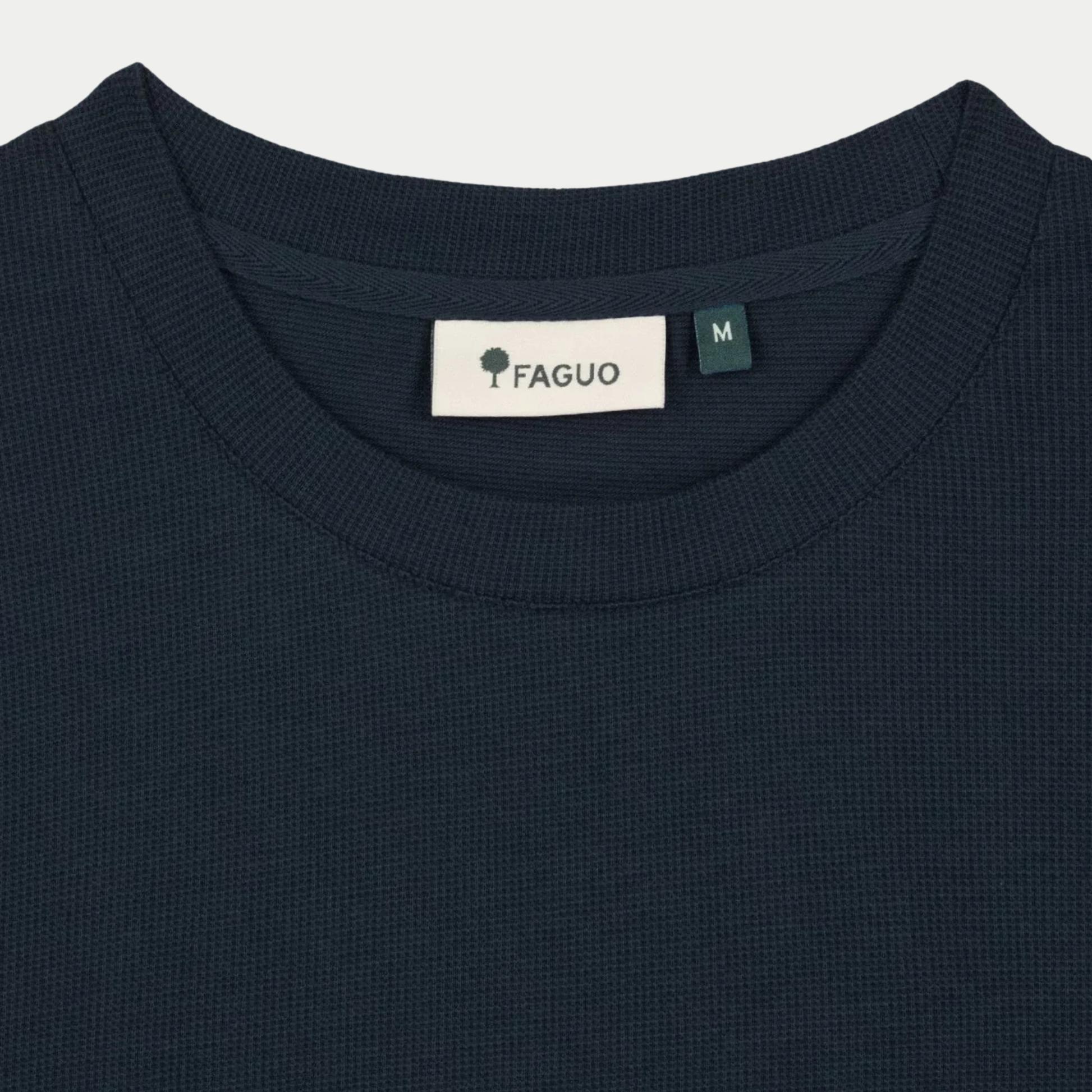 Gros plan du col rond côtelé et de l'étiquette FAGUO du t-shirt Bailly bleu marine