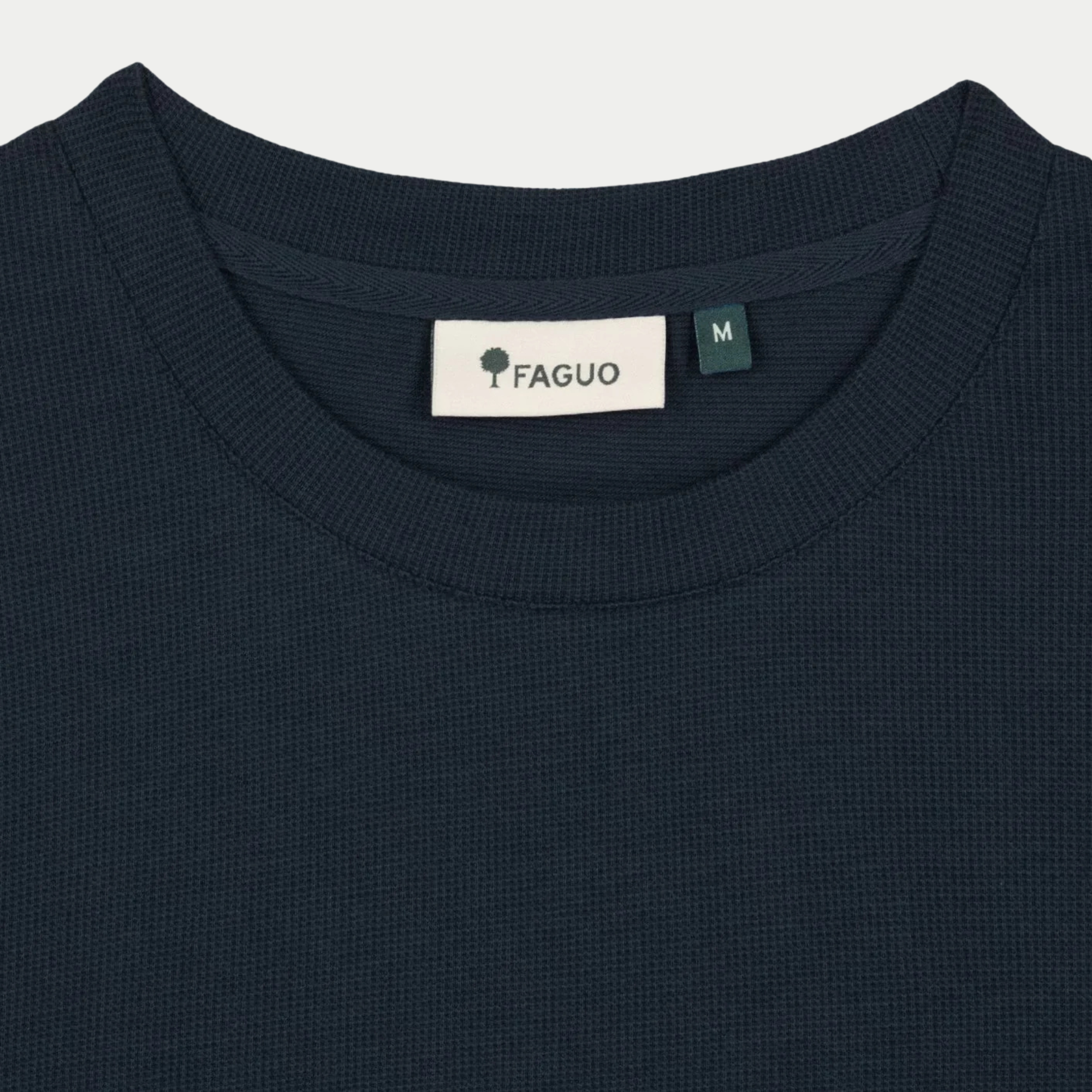 Gros plan du col rond côtelé et de l'étiquette FAGUO du t-shirt Bailly bleu marine