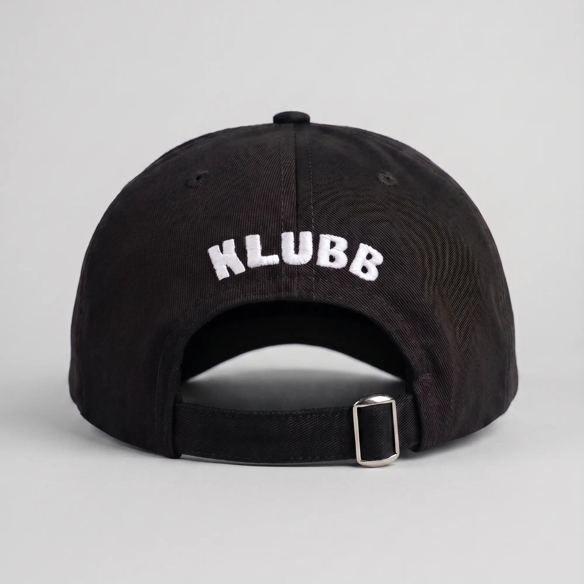 Dos de la casquette Klubb noire : lettrage KLUBB blanc brodé en arc au-dessus de la sangle et de sa boucle métal