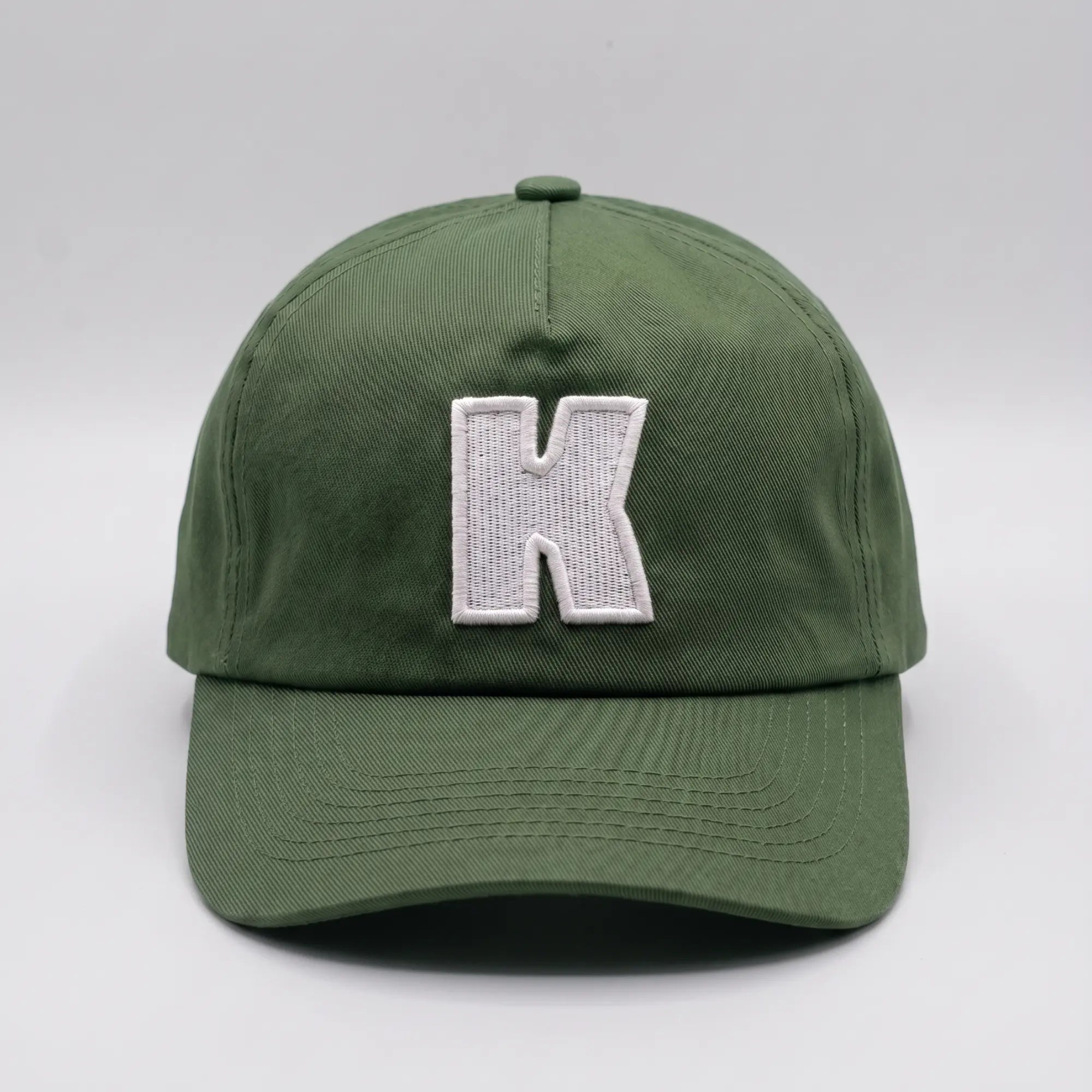 Casquette baseball Klubb vert olive grisé vue de face, grand K blanc brodé au centre du panneau avant et visière courbée