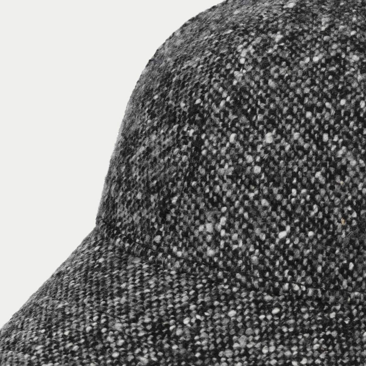 Gros plan du tweed Donegal noir piqué de neps blancs sur la calotte de la casquette Stetson