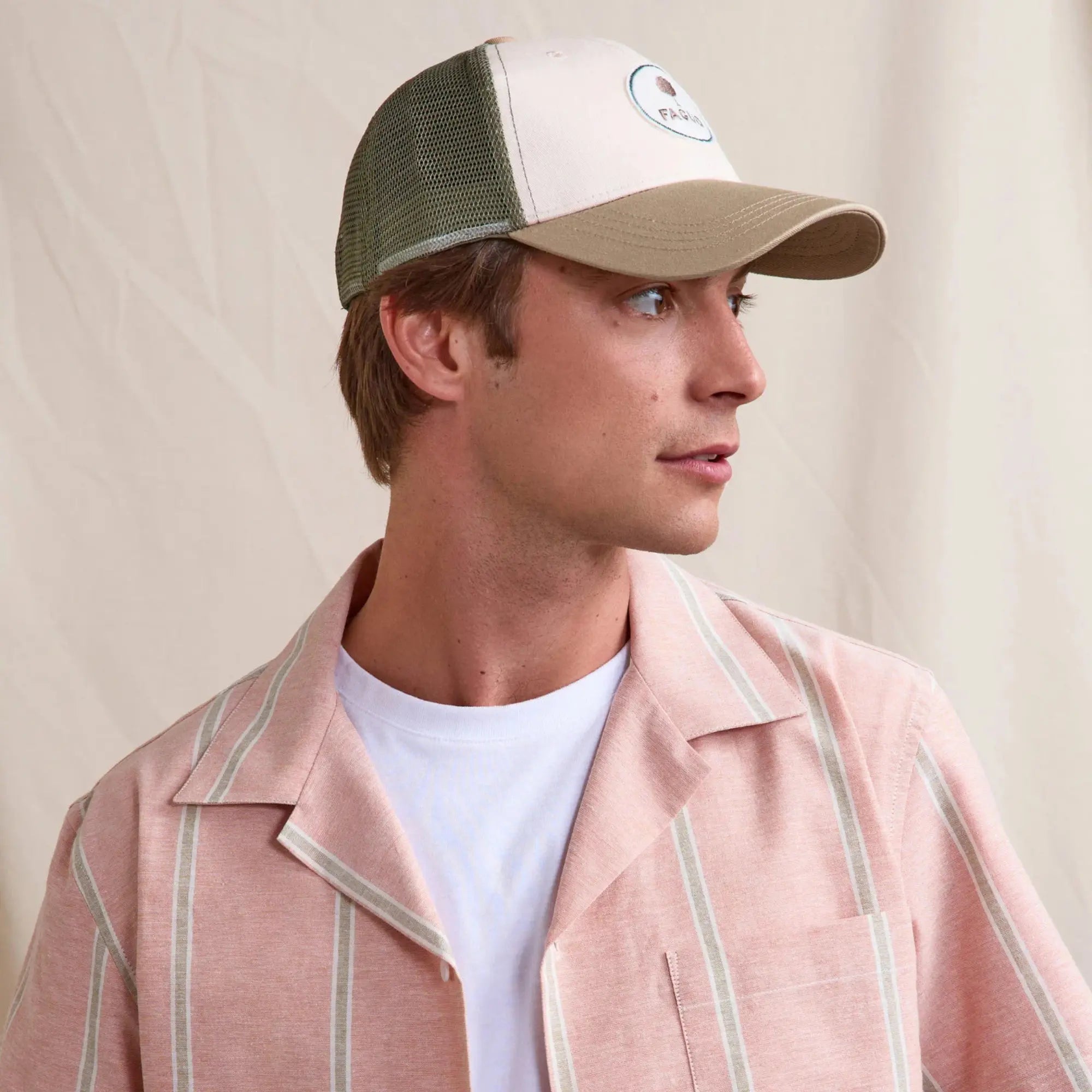 Casquette trucker Faguo beige et vert portée de profil, badge brodé sur le panneau écru et visière sable