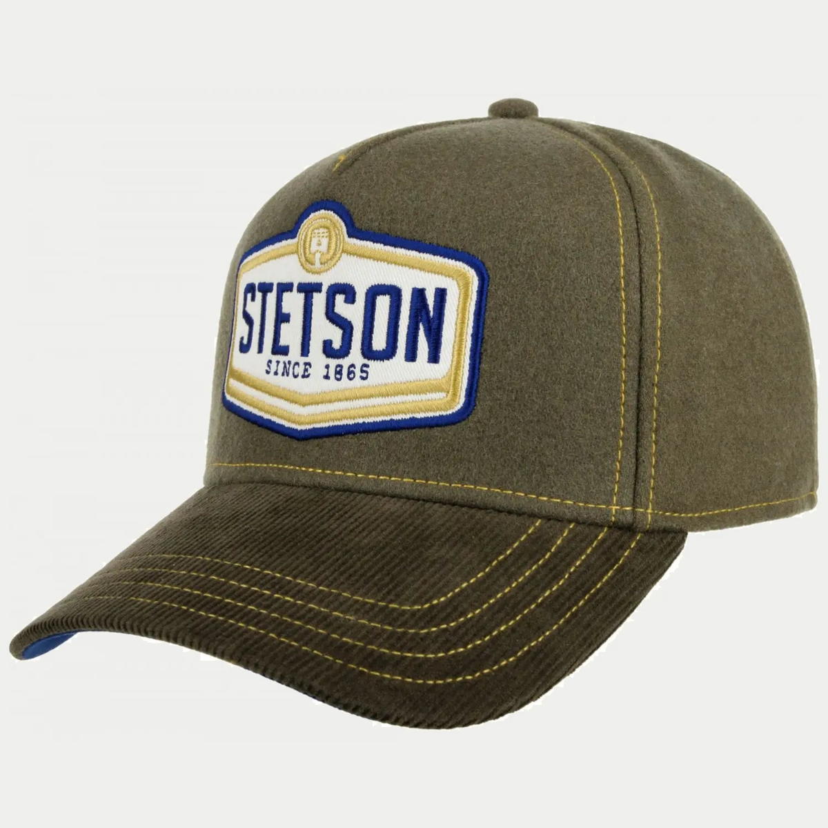 Casquette trucker Piston Stetson olive de profil : calotte en laine, visière en velours côtelé et écusson brodé Since 1865
