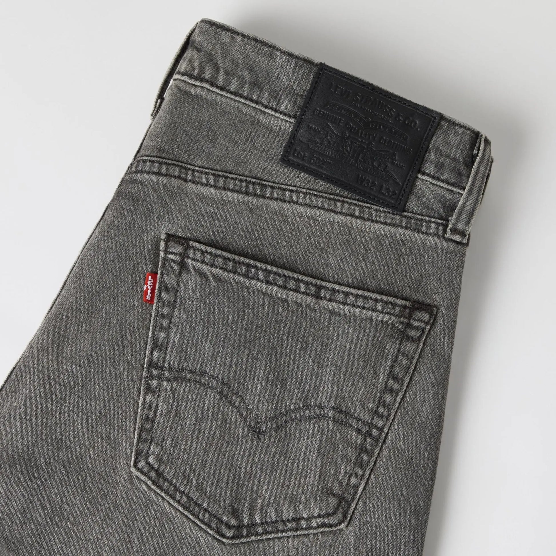 Détail du jean Levi's 502 Taper Granite Shadow : poche arrière arquée, tab rouge et patch cuir Lot 502