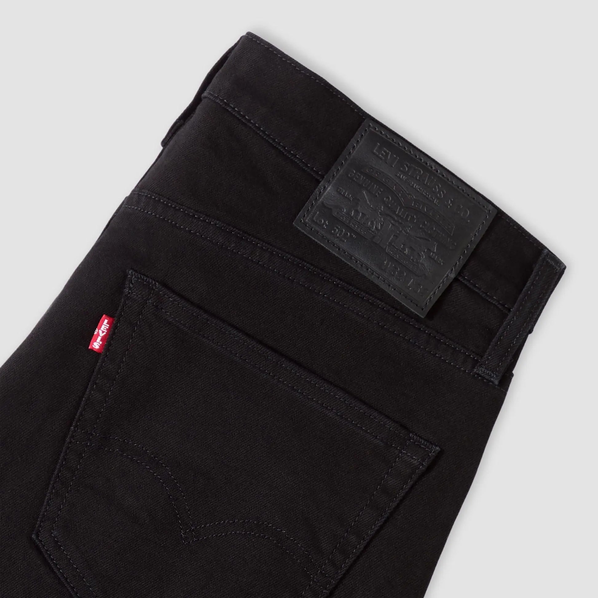 Détail dos du jean Levi's 502 Taper Sta-Dark Black : patch cuir gaufré Lot 502, red tab rouge et surpiqûre arcuate
