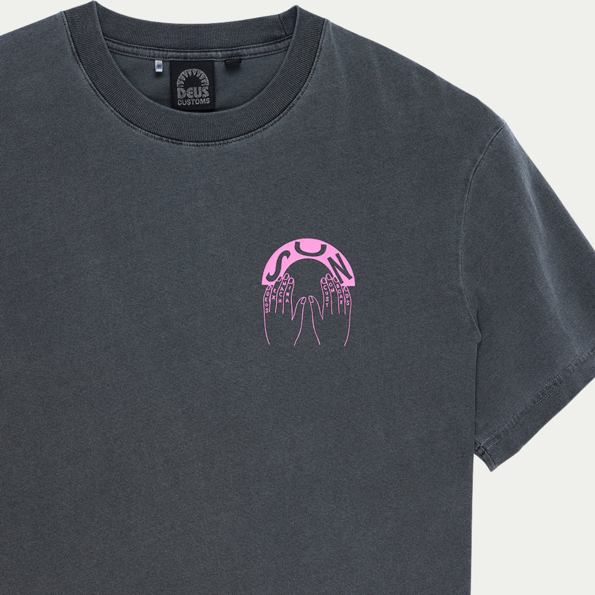 Détail encolure du T-shirt Catchin Rays anthracite, étiquette tissée Deus Customs et imprimé rose sur la poitrine