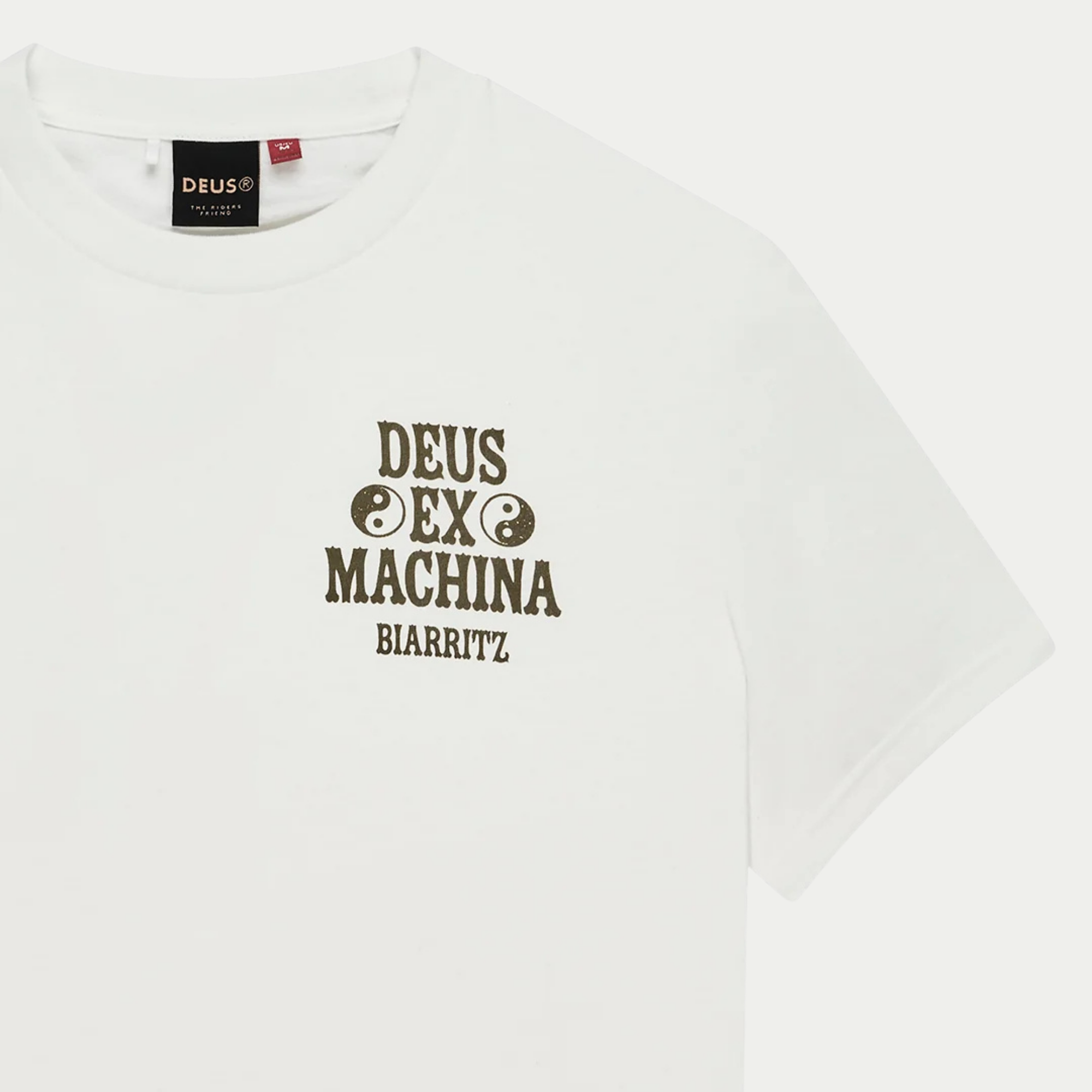 Détail poitrine du T-shirt Biarritz Ceramic blanc : logo olive Deus Ex Machina Biarritz et étiquette de col DEUS