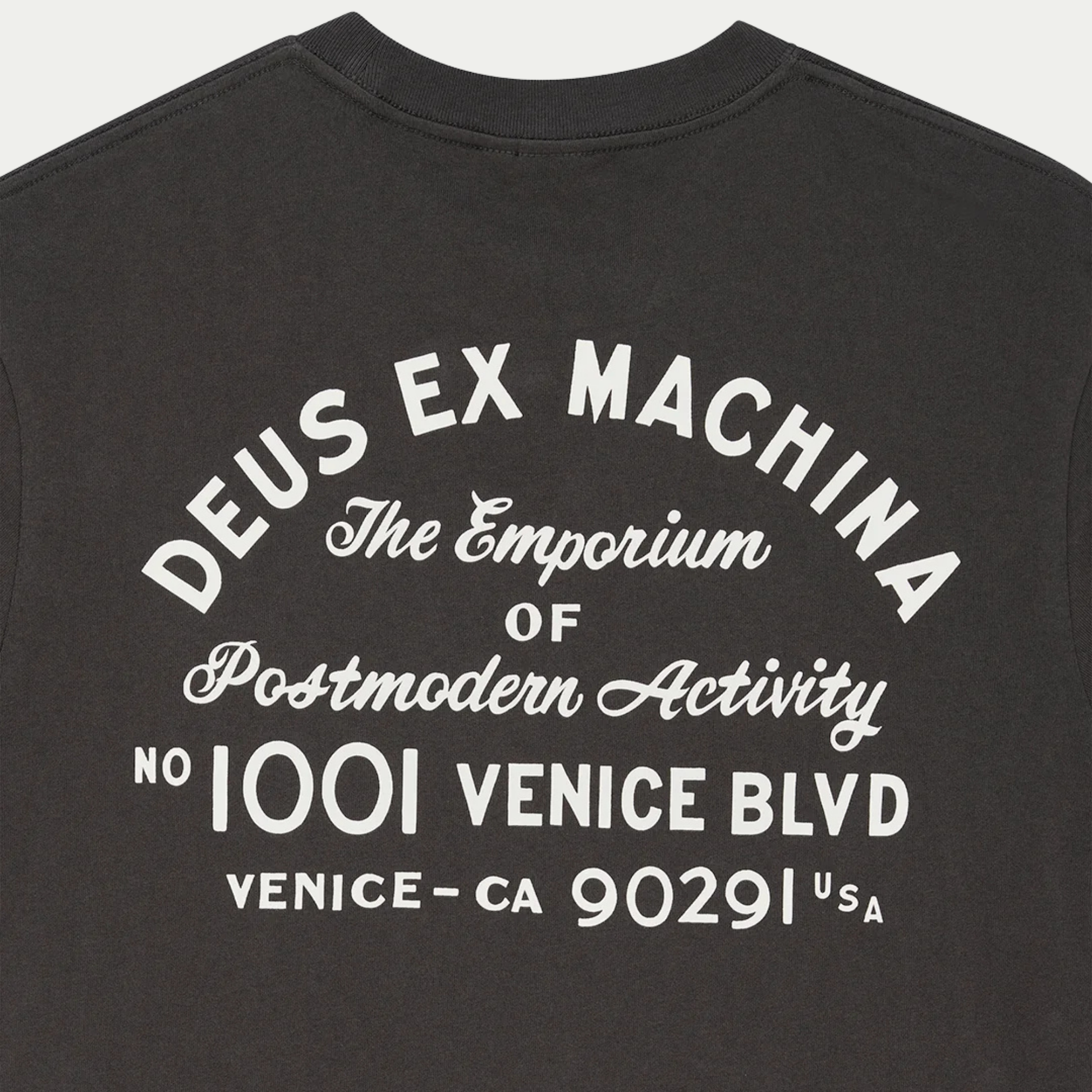 Gros plan du dos du T-shirt Park anthracite : lettrage arqué Deus Ex Machina et adresse Venice imprimés en blanc cassé