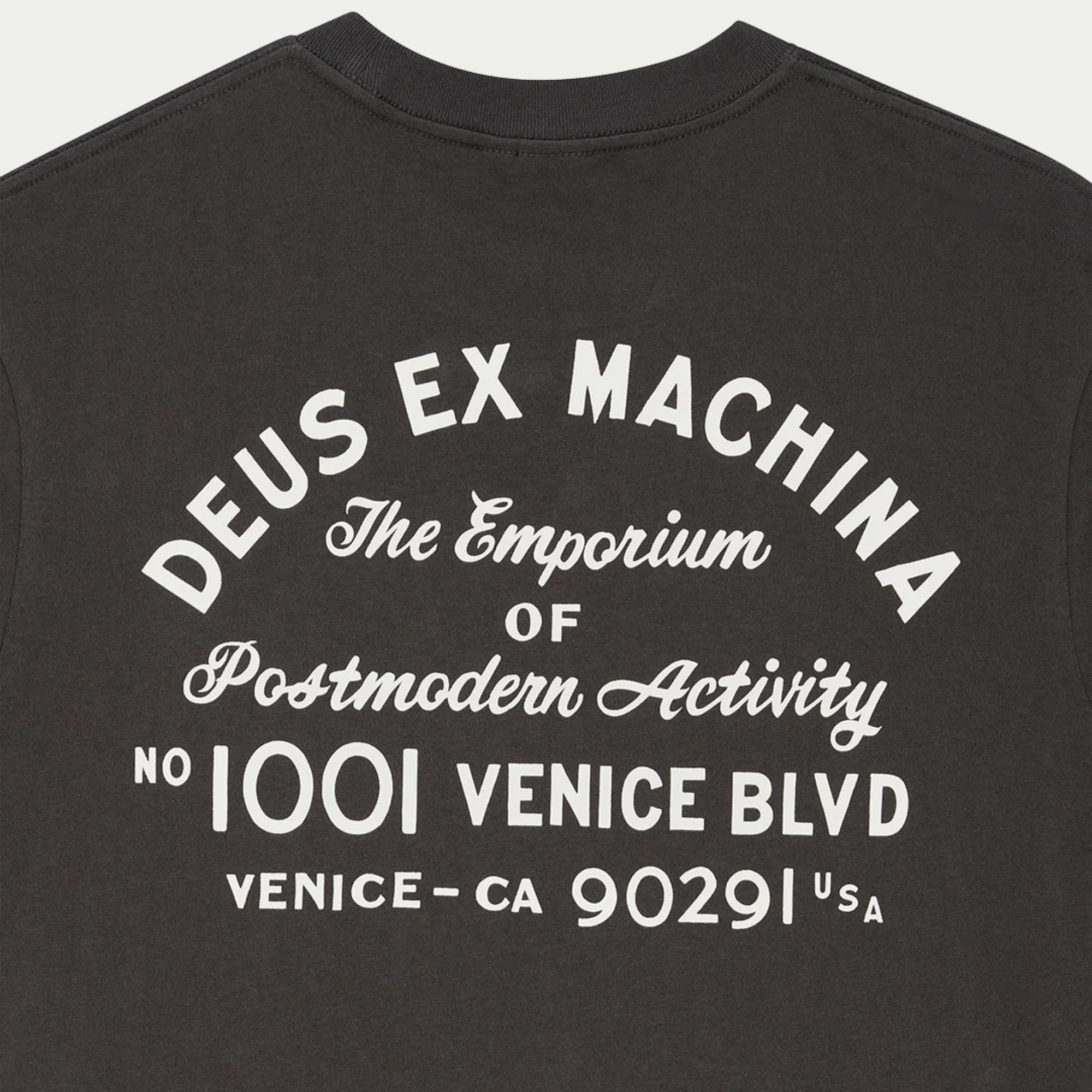 Gros plan du dos du T-shirt Park anthracite : lettrage arqué Deus Ex Machina et adresse Venice imprimés en blanc cassé
