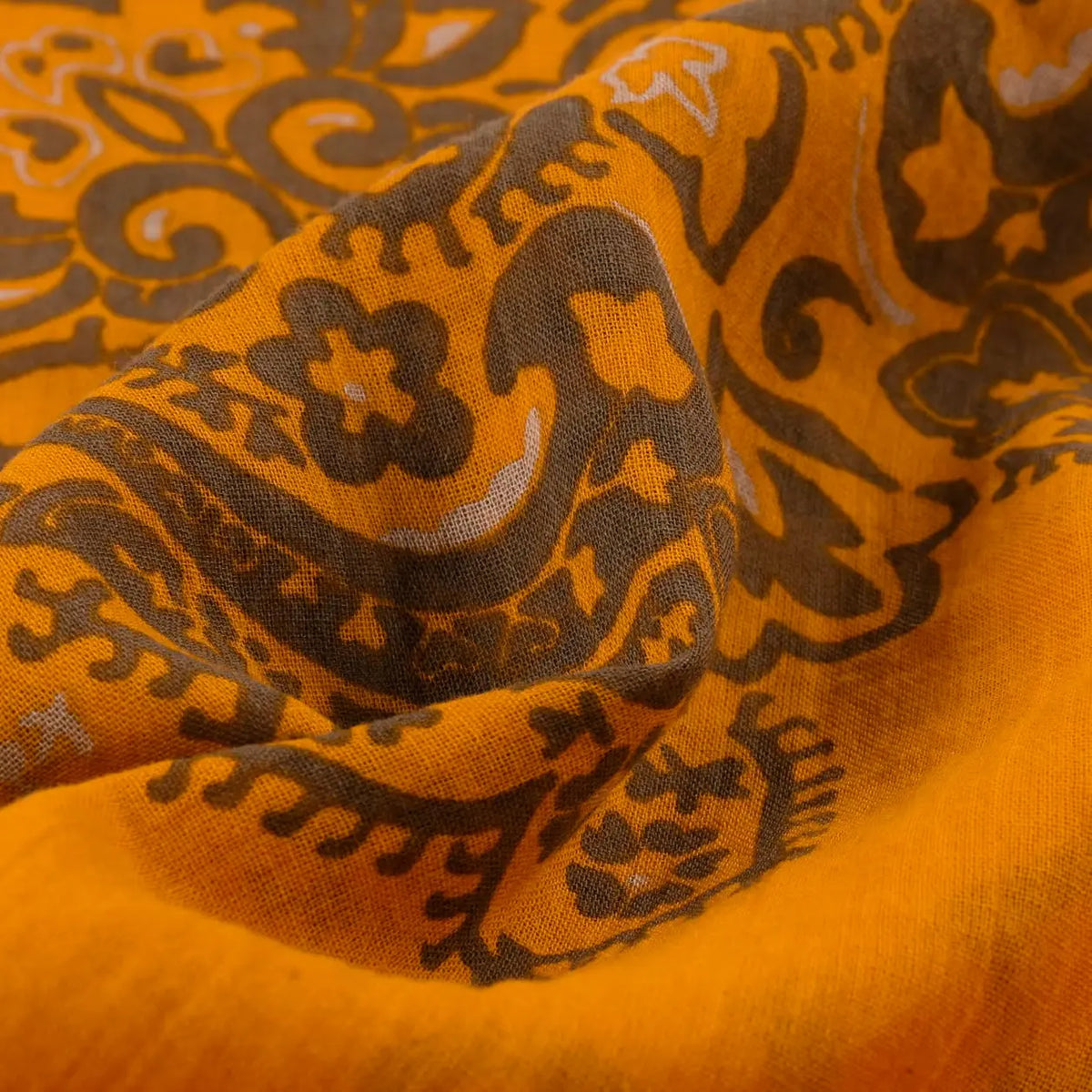 Gros plan du coton jaune safran froissé, motif paisley brun kaki finement imprimé