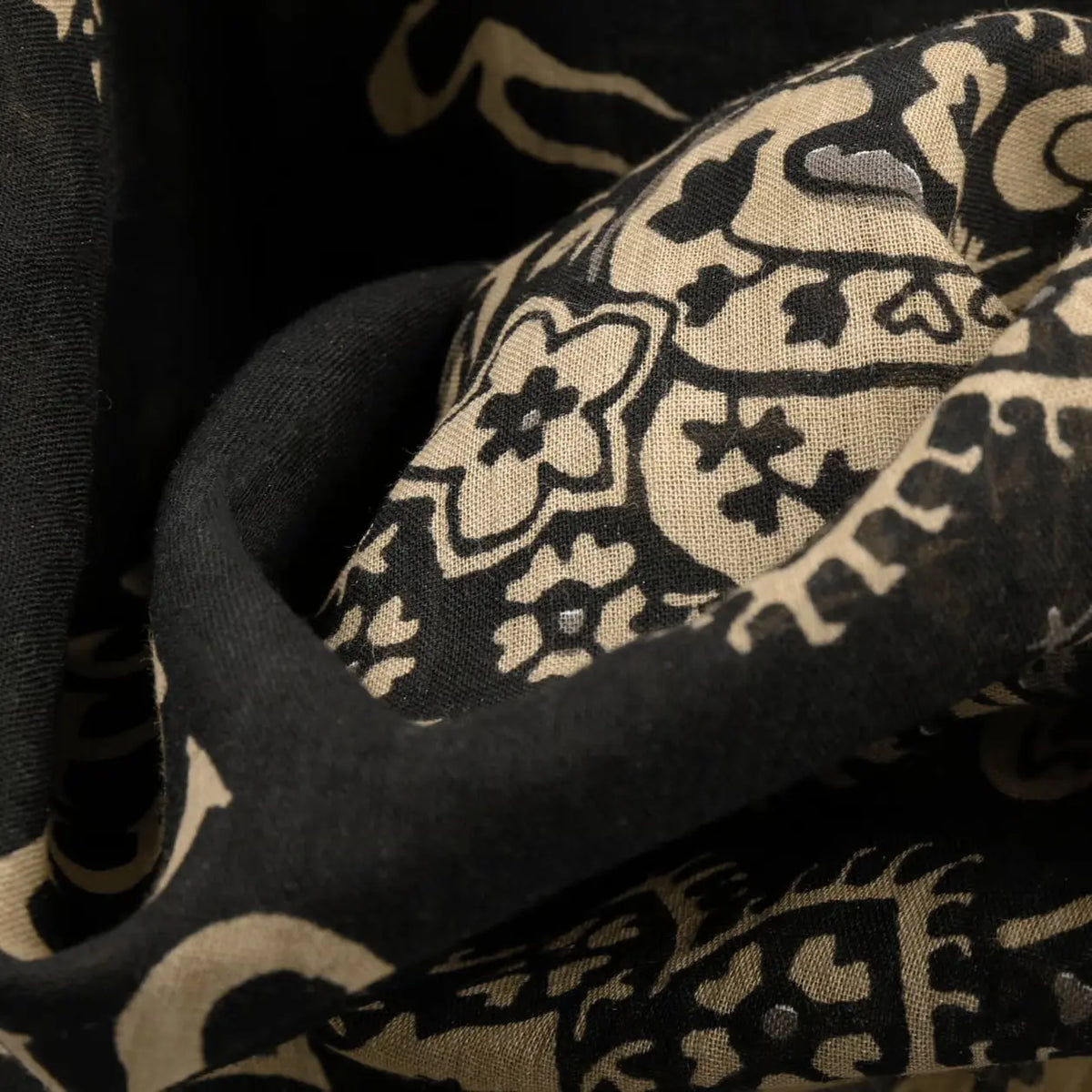 Gros plan du coton noir froissé, motif paisley sable et fleurs stylisées
