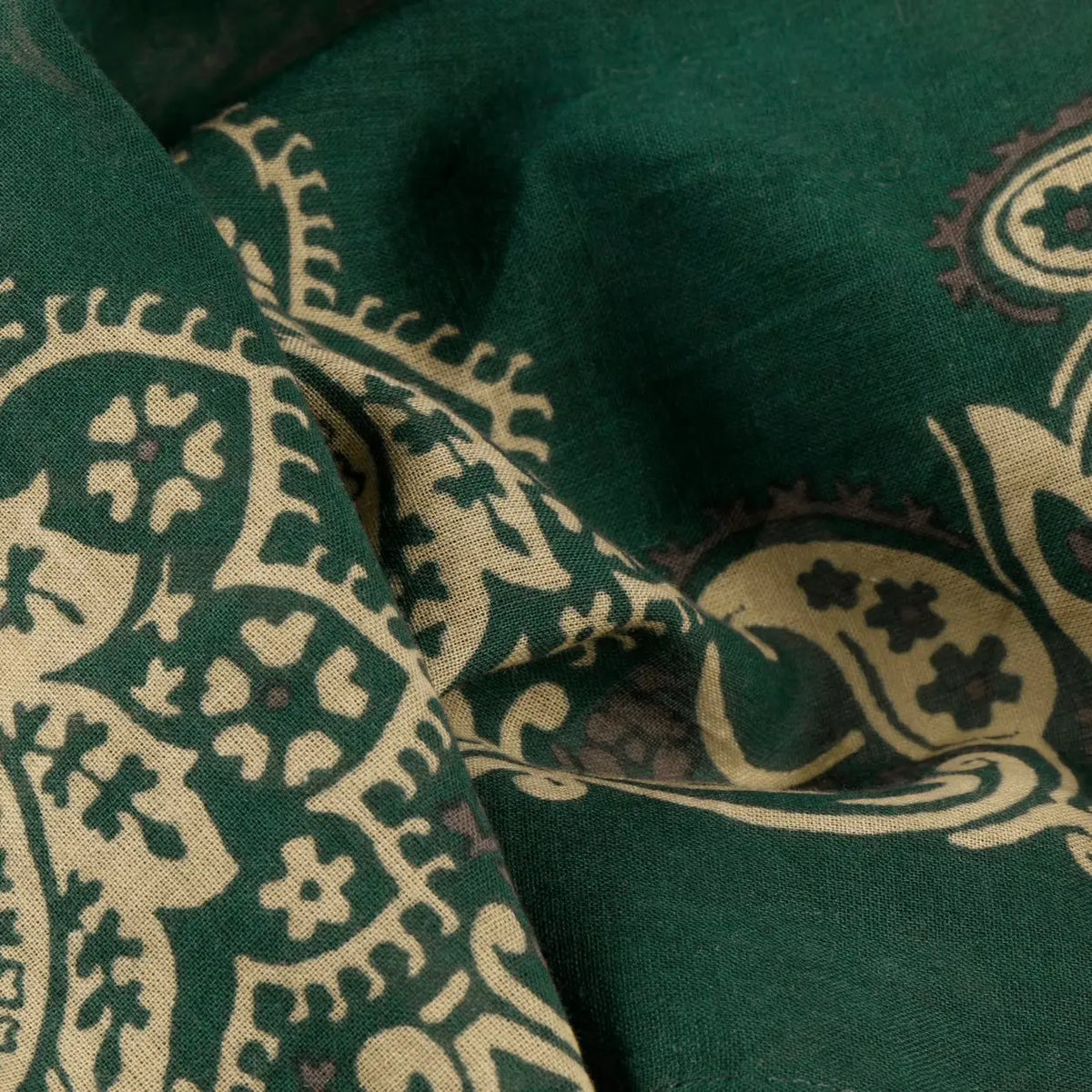 Gros plan du coton vert sapin froissé, arabesques paisley beige et brun