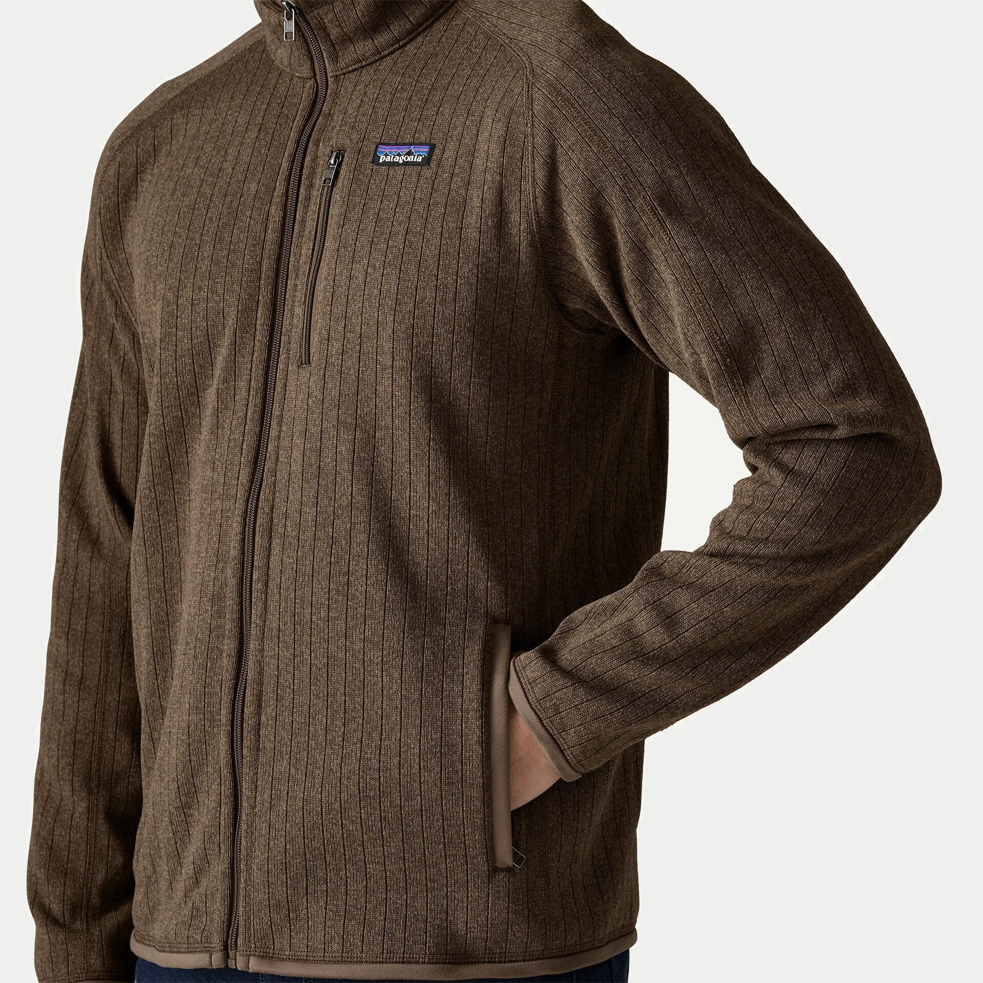 Détail de la polaire Better Sweater Marlow Brown Patagonia, main glissée dans la poche zippée sous le logo