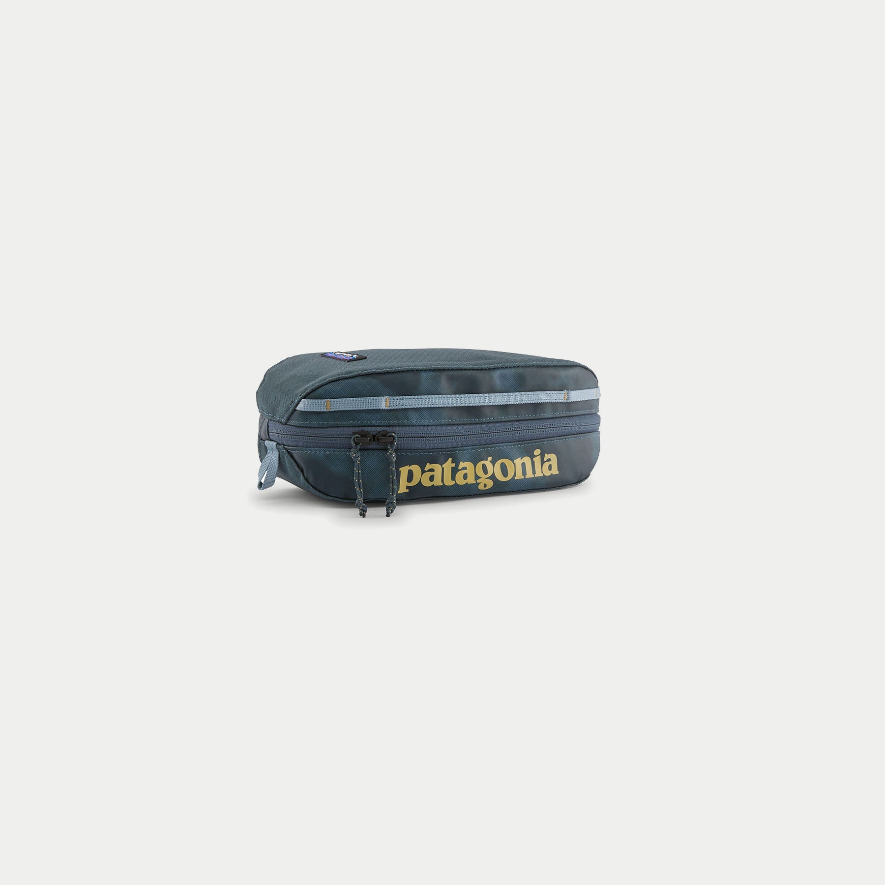 Cube Black Hole 3L Patagonia bleu ardoise, trois quarts : imprimé Sastrugi ton sur ton, zip double cordon, poignée claire.