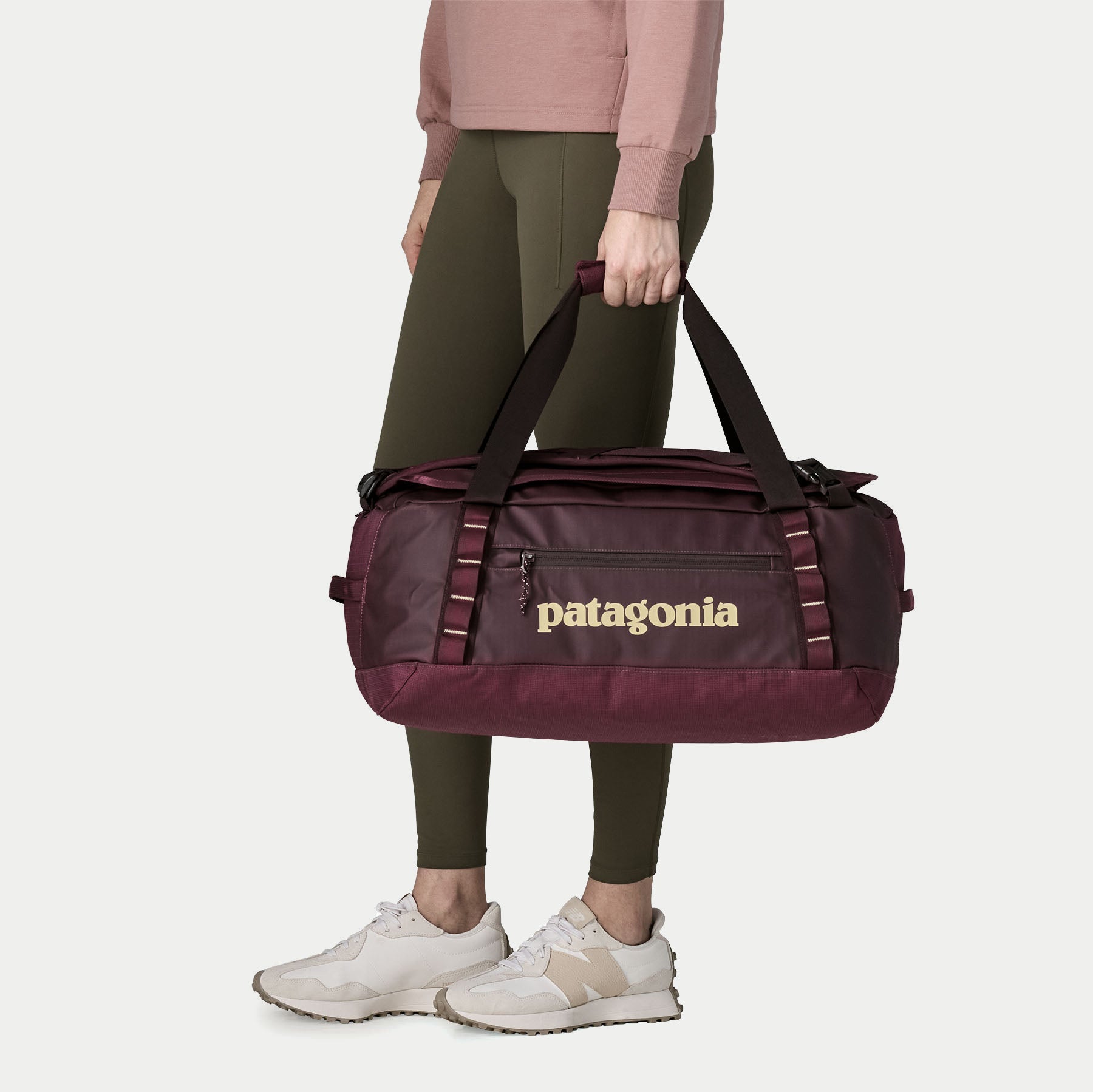 Duffel Black Hole 40L Berry Fig porté à la main par ses deux poignées sanglées jointives