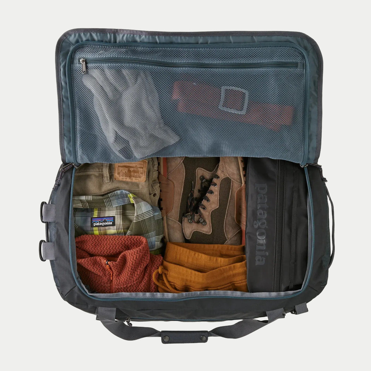 Black Hole Duffel 55L Smolder Blue ouvert et rempli, poche filet zippée dans le rabat