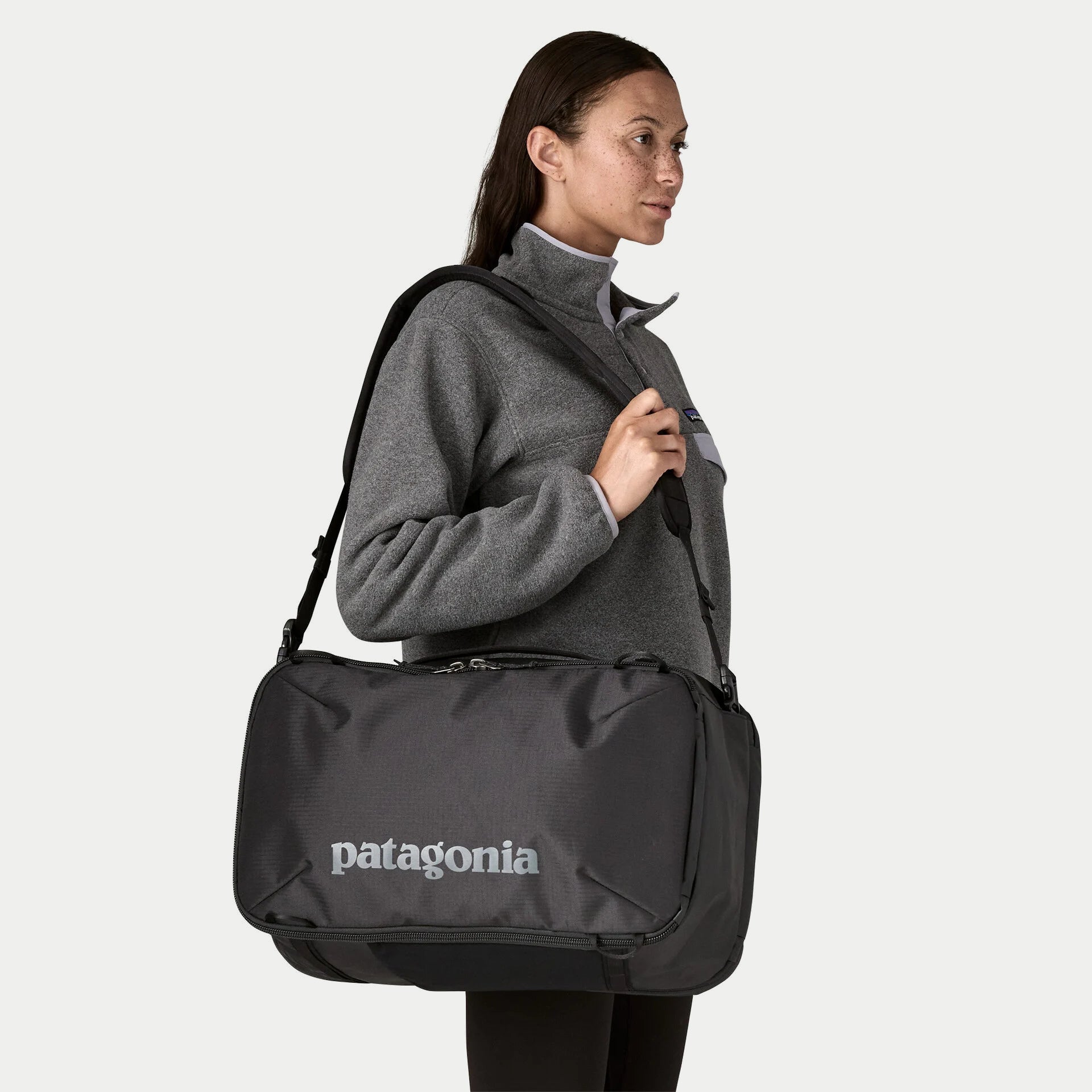 Black Hole Mini MLC 30L noir Patagonia porté en bandoulière à l’horizontale, sangles rangées