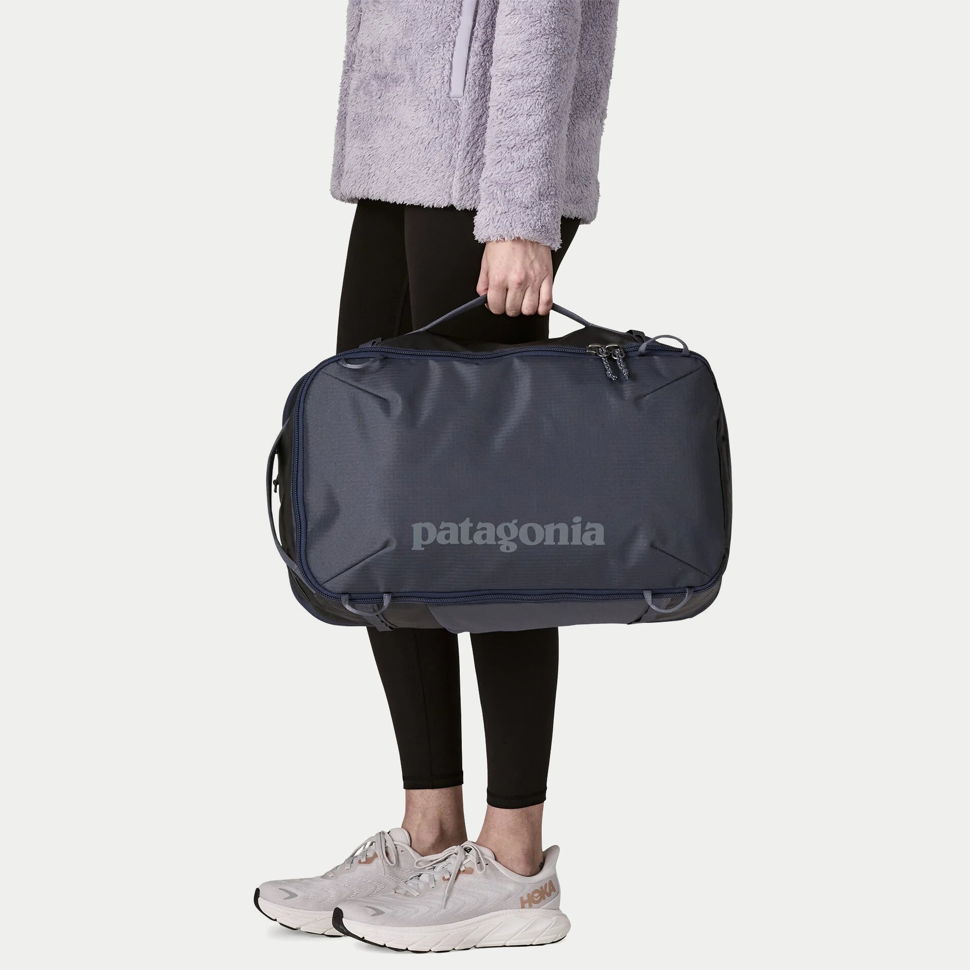 Sac Black Hole Mini MLC 30L Smolder Blue Patagonia porté à la main par la poignée haute, en mode sac de voyage