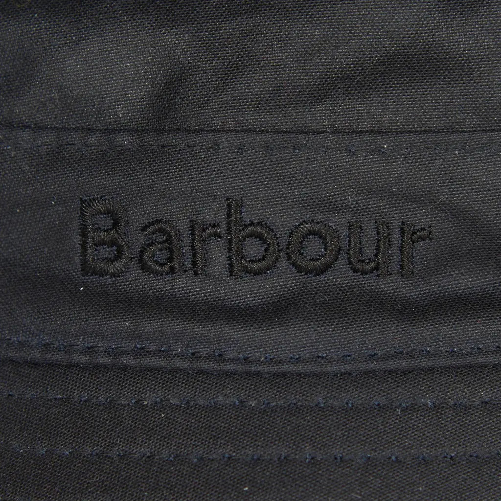 Gros plan du logo brodé ton sur ton sur le bandeau du bob Bleu Marine