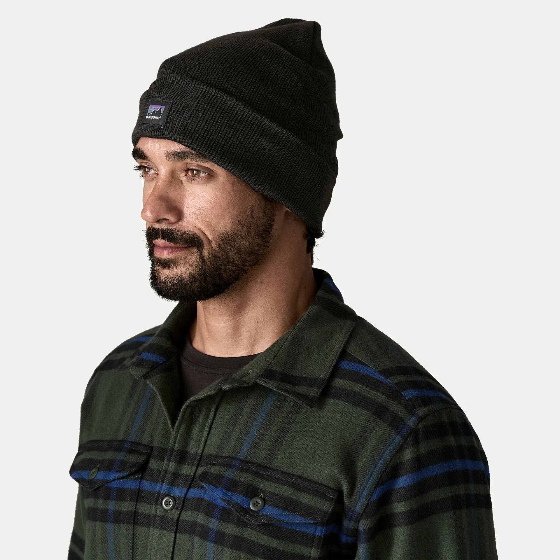 Bonnet Everyday Patagonia noir porté de profil, revers rabattu et étiquette P-6 tissée sur le côté