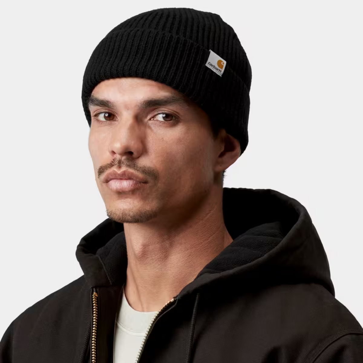 Bonnet Gabe noir Carhartt WIP porté, revers remonté au-dessus des oreilles, étiquette tissée sur le côté