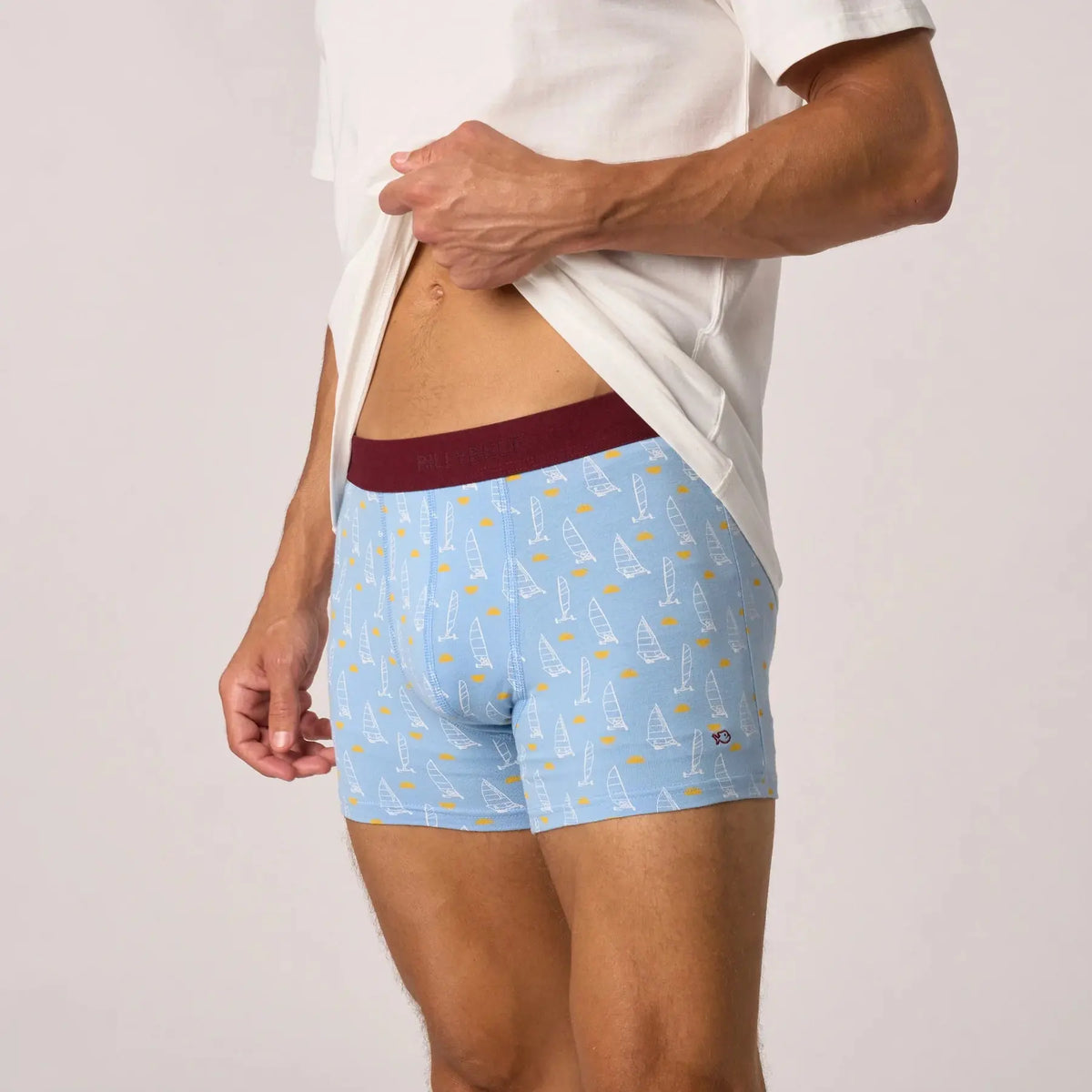 Boxer Land Sailer porté de profil, chars à voile au trait blanc sur bleu ciel et ceinture bordeaux foncé