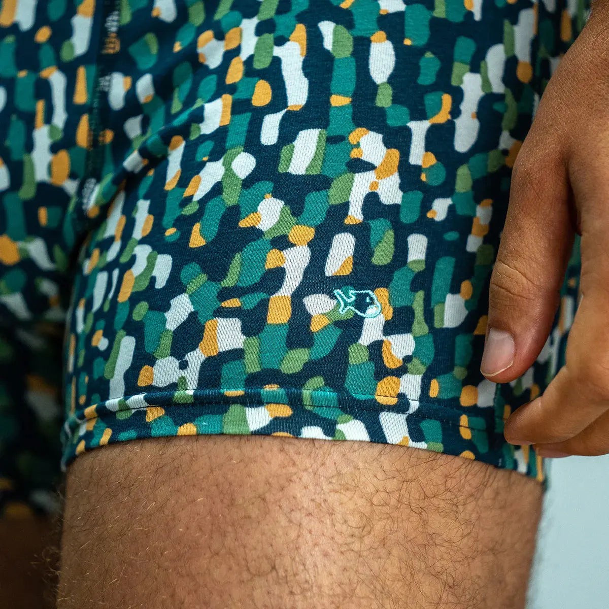 Détail du boxer Mirage : poisson brodé bleu ciel sur la jambe, semis de taches vertes, blanches et ocre