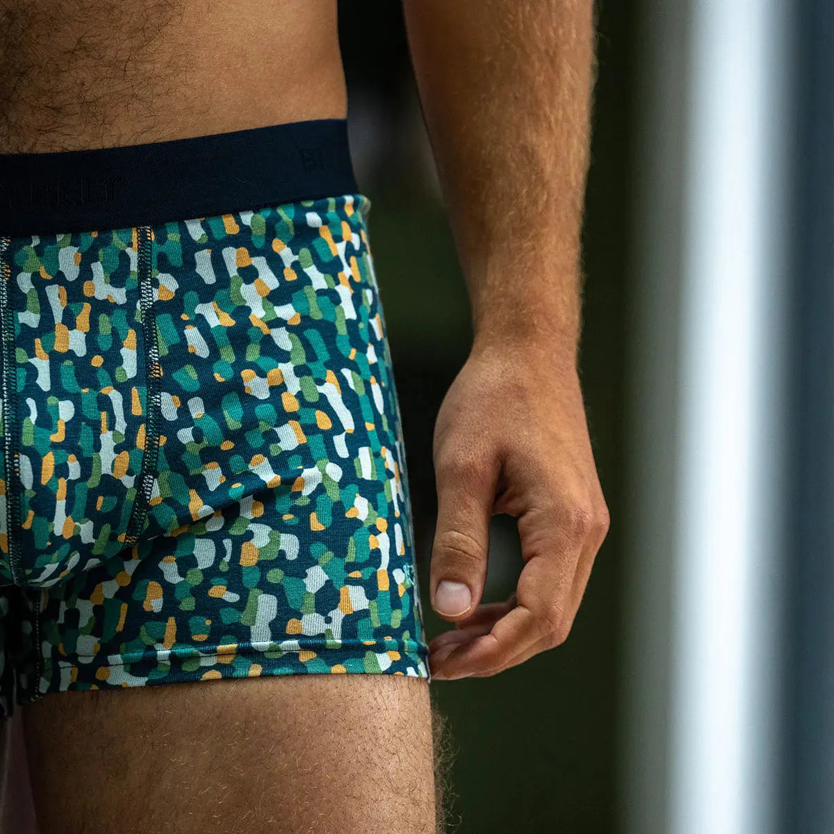 Boxer Mirage vu de profil, motif moucheté façon terrazzo vert, blanc et jaune sur fond Bleu Marine