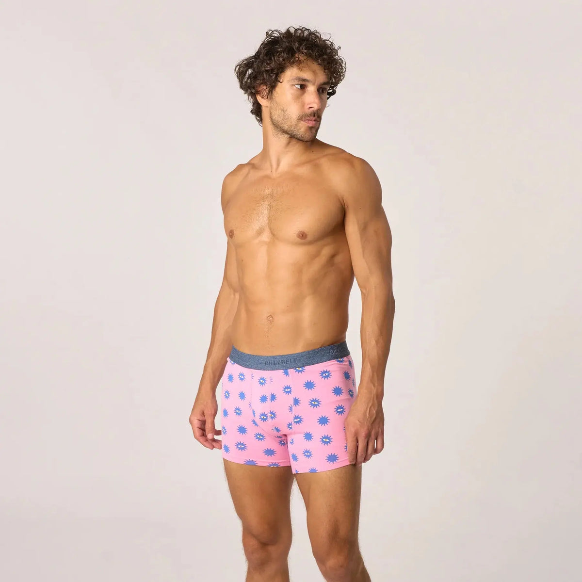 Boxer Suneyes vu en pied, fond rose bonbon parsemé de soleils bleus dont certains ouvrent un œil jaune