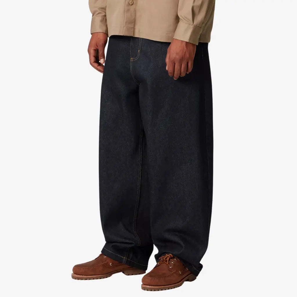 Brandon Pant Blue Rigid porté de profil : couture de côté et ourlet simple sur un indigo brut presque noir