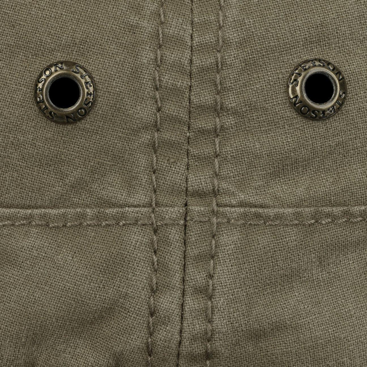 Macro des deux œillets métal et des surpiqûres du bandeau, toile olive délavée