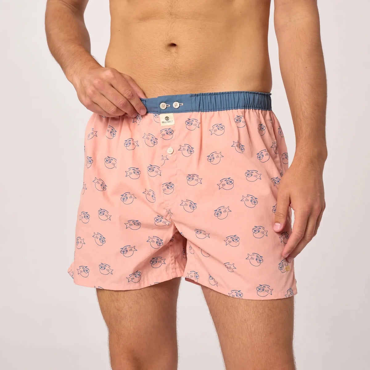 Caleçon Billychill porté de face, têtes de poisson à lunettes de soleil bleues sur fond rose poudré