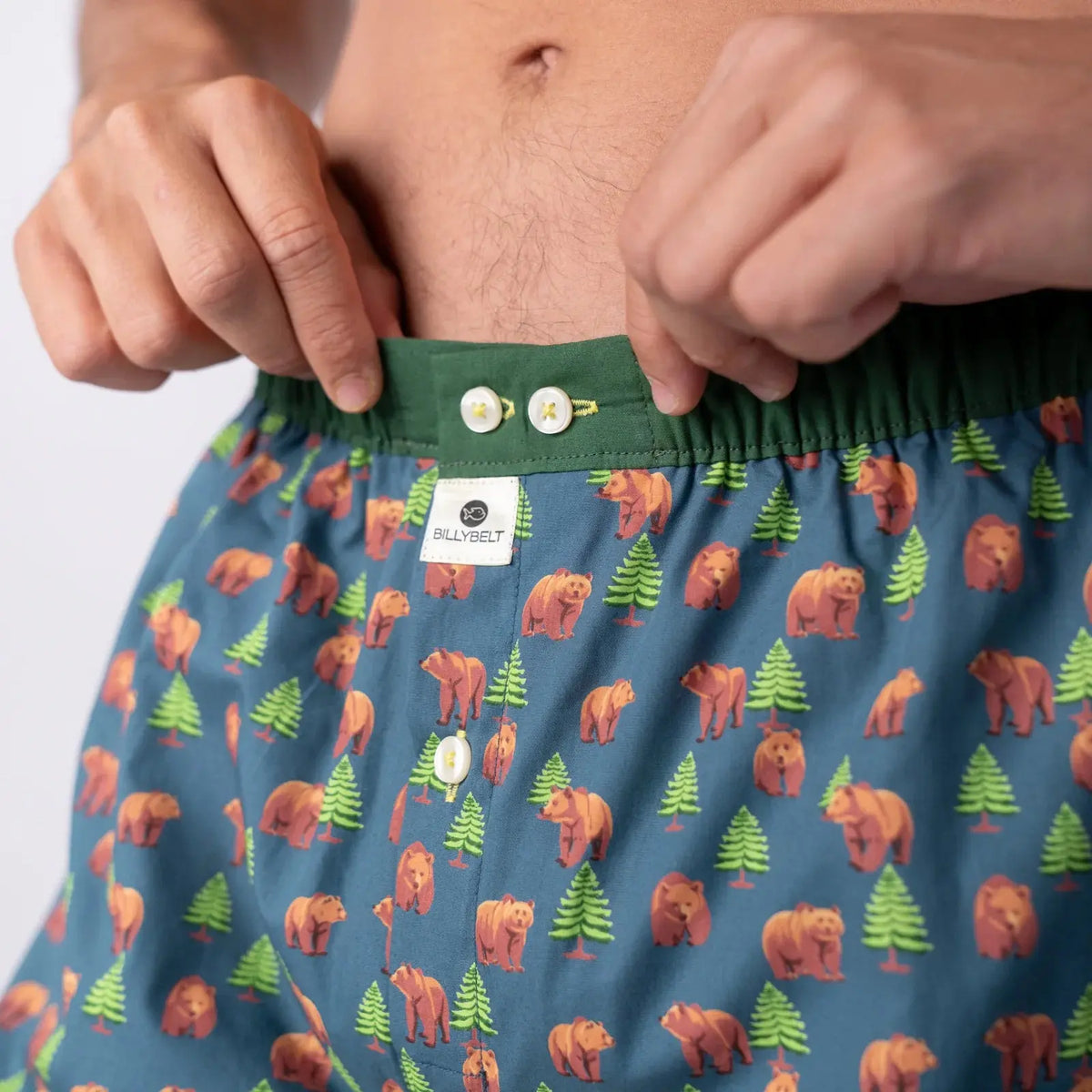 Gros plan sur la ceinture vert sapin, ses deux boutons nacrés et l'étiquette tissée BillyBelt du caleçon
