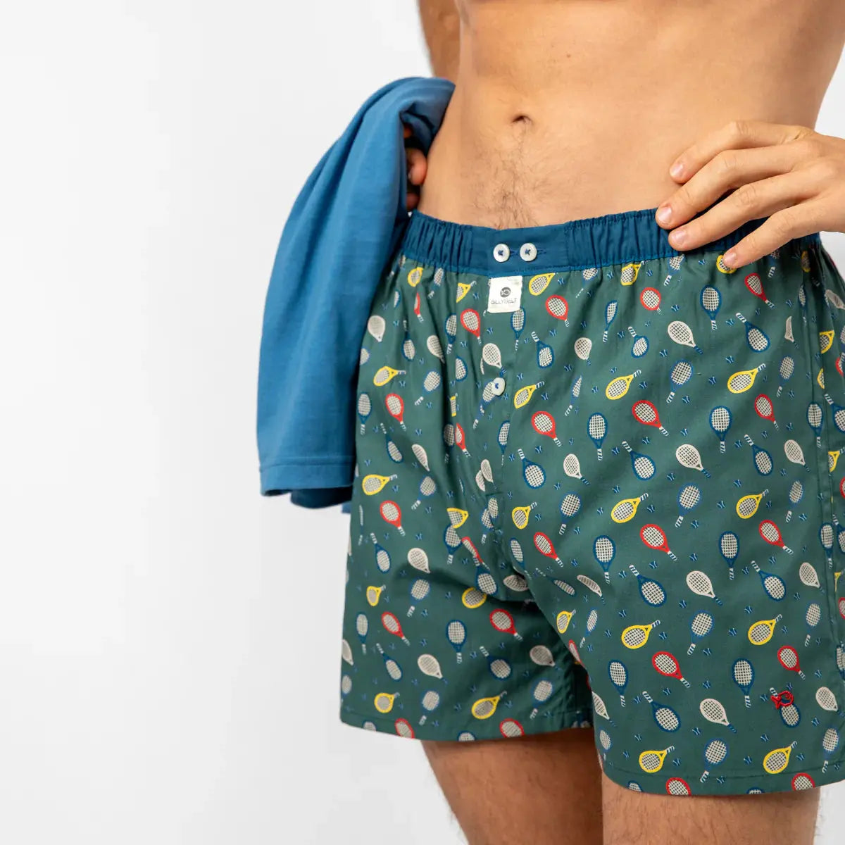 Caleçon Wimbledon porté, raquettes de tennis et petites balles bleues sur fond vert sapin, ceinture bleue