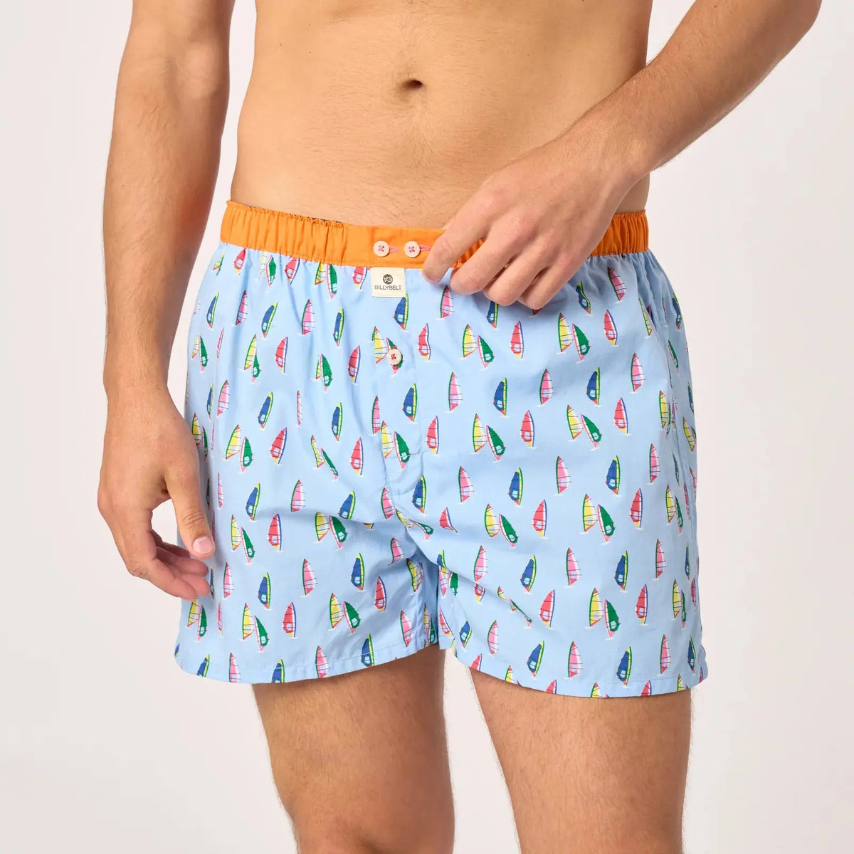 Gros plan sur la ceinture orange vif à deux boutons nacrés et l'étiquette BillyBelt du caleçon Windsurf