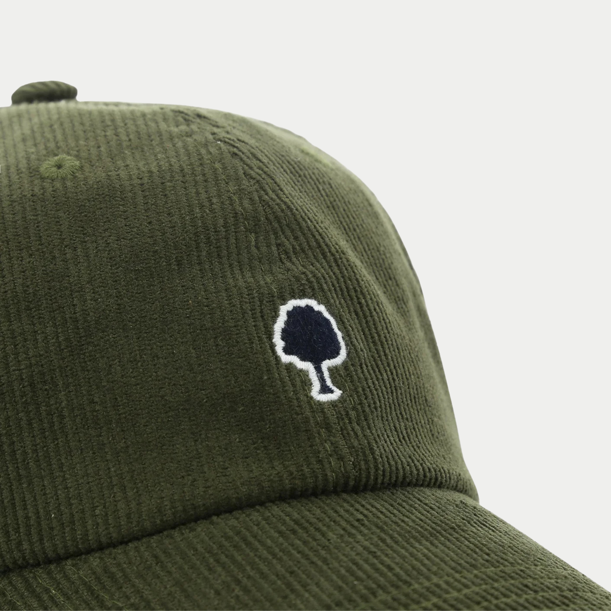Macro du velours côtelé kaki de la casquette Faguo et de sa broderie arbre marine cernée de blanc