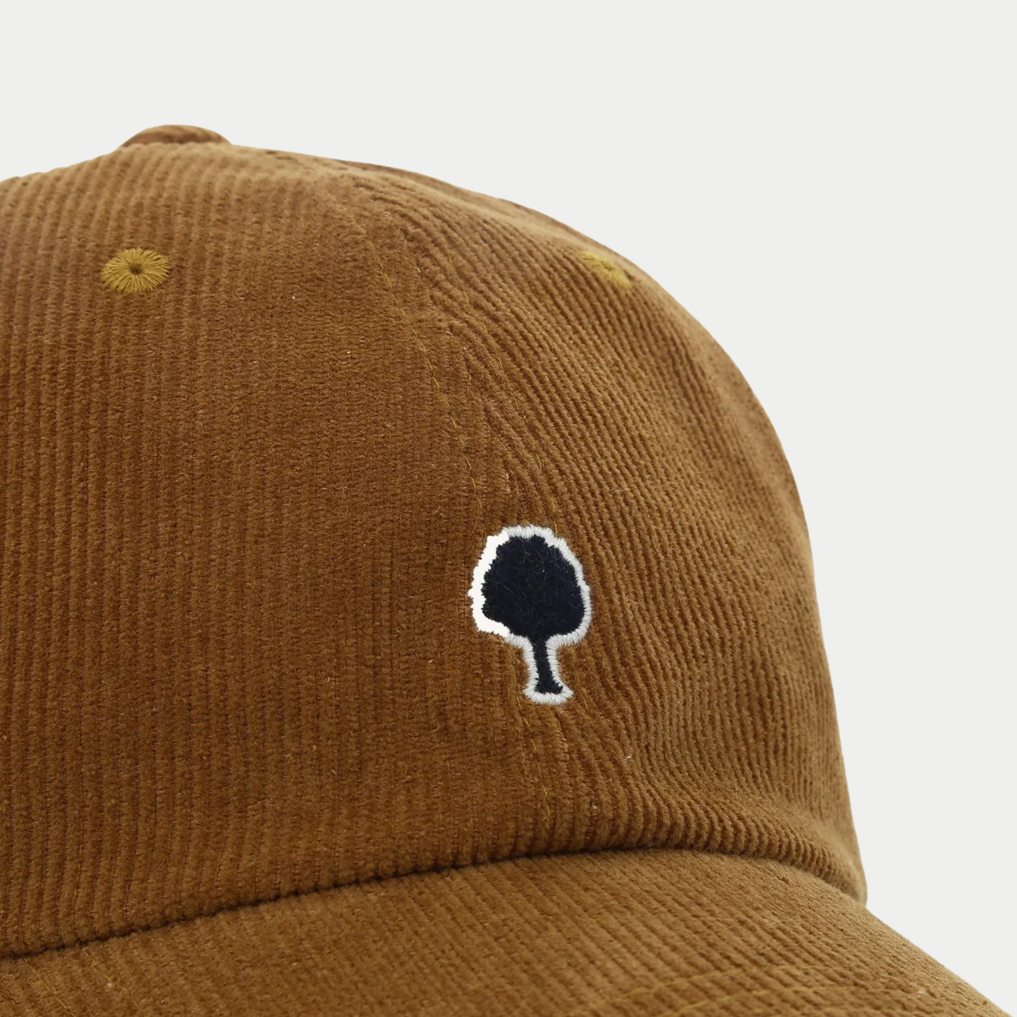 Détail du velours côtelé camel et de la broderie arbre marine cerclée de blanc, casquette Faguo