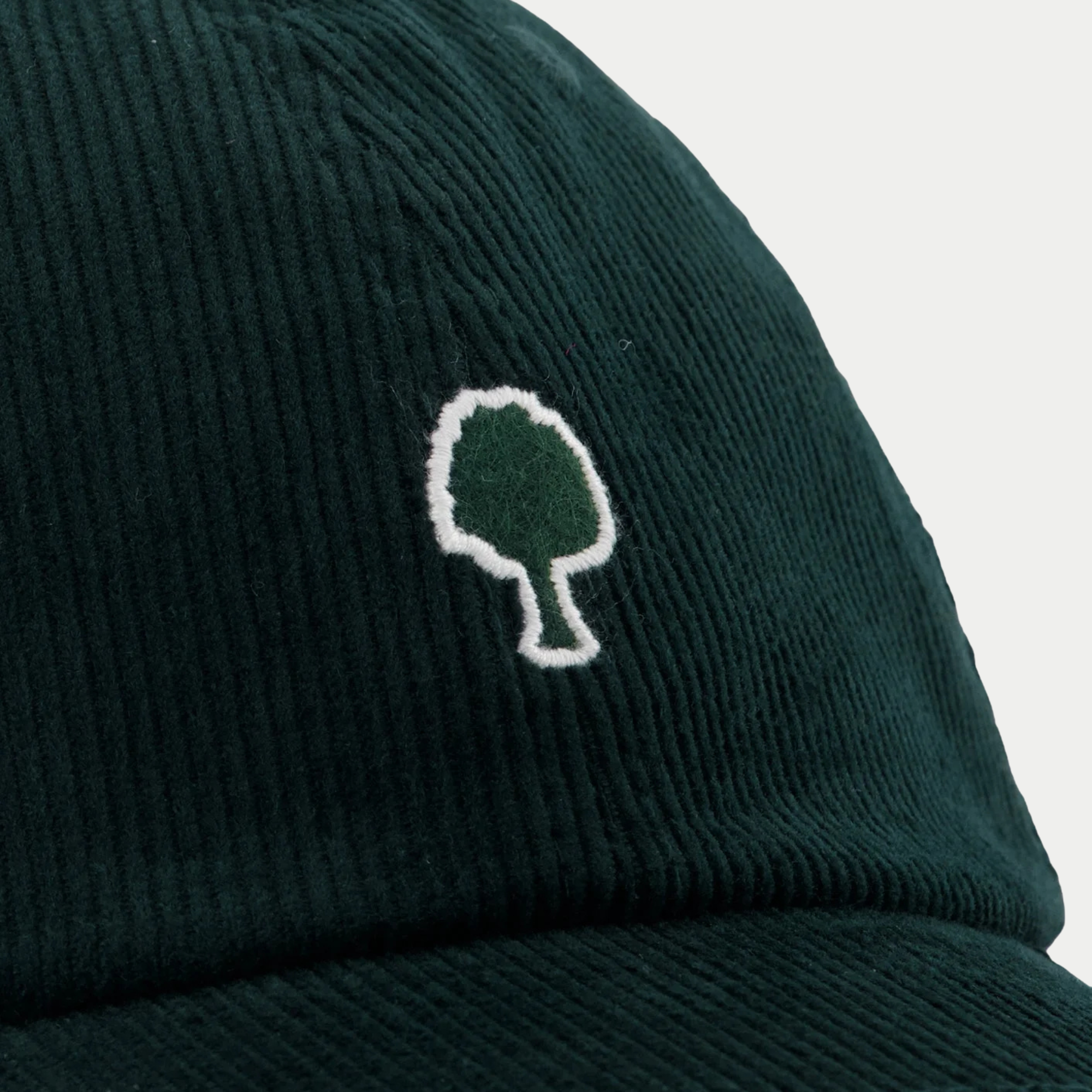 Détail du velours côtelé vert sapin et de la broderie arbre cerclée de blanc, casquette Faguo