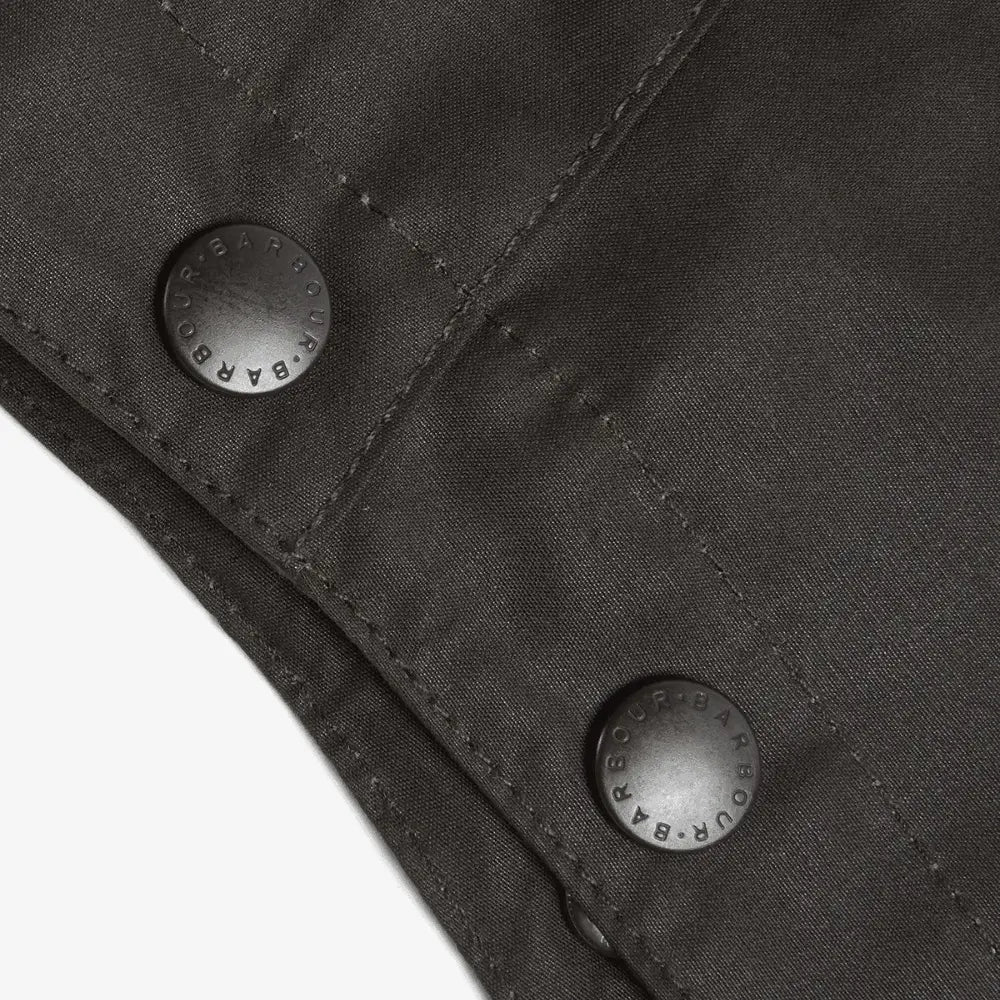 Deux pressions en métal vieilli et surpiqûres en biais sur le coton ciré olive