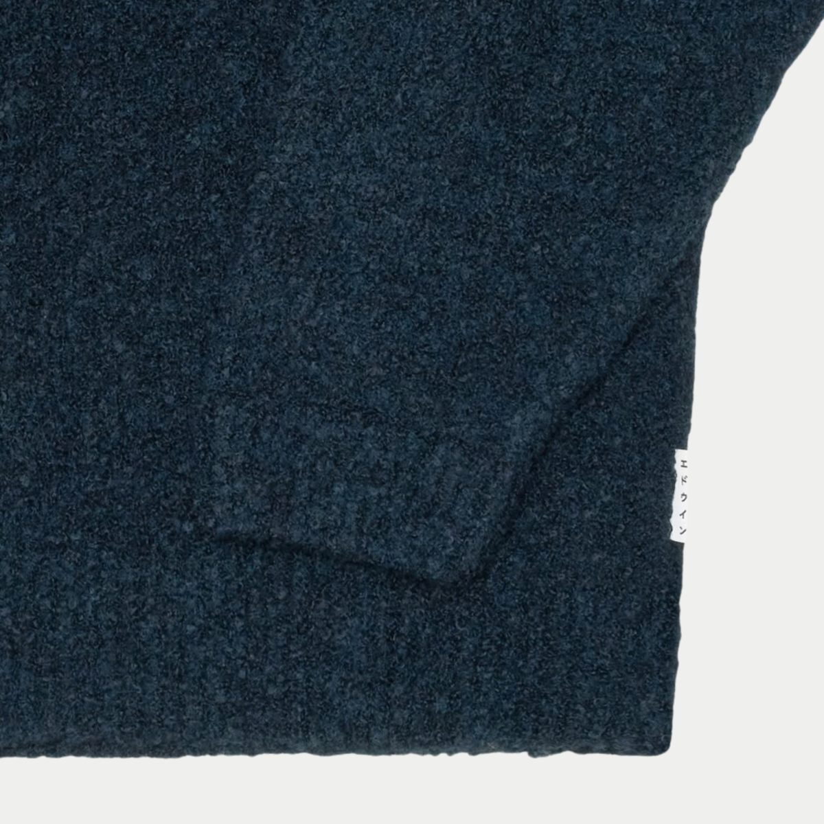 Gros plan sur la maille bouclette chinée, le poignet et l’ourlet côtelés du cardigan Gemini bleu marine