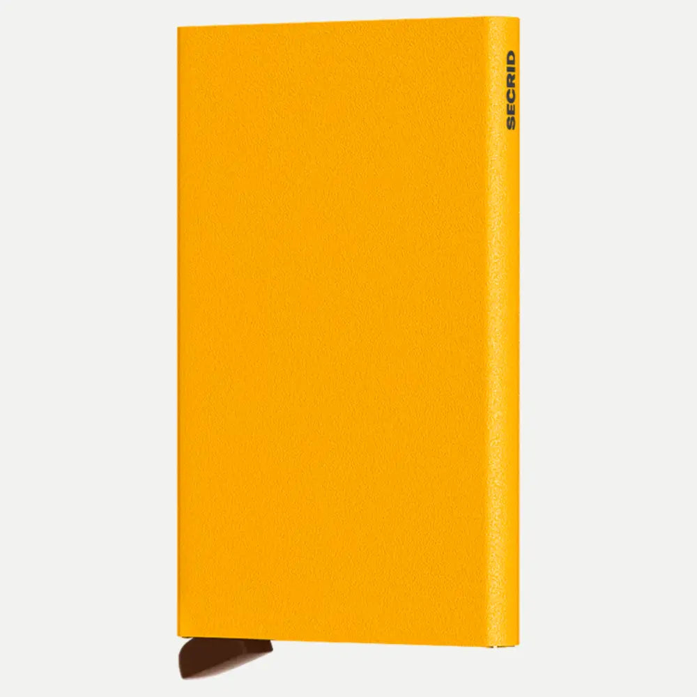 Porte-cartes aluminium jaune ocre à texture poudrée, logo gravé sombre sur la tranche