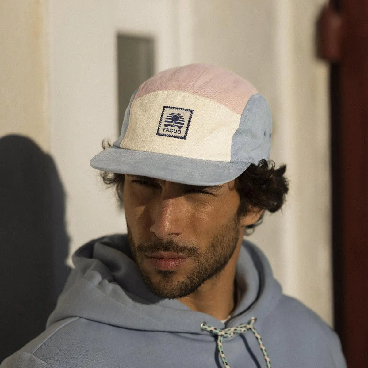 Casquette 5 panneaux rose pâle et bleu gris portée de face en extérieur, visière plate baissée sur le front