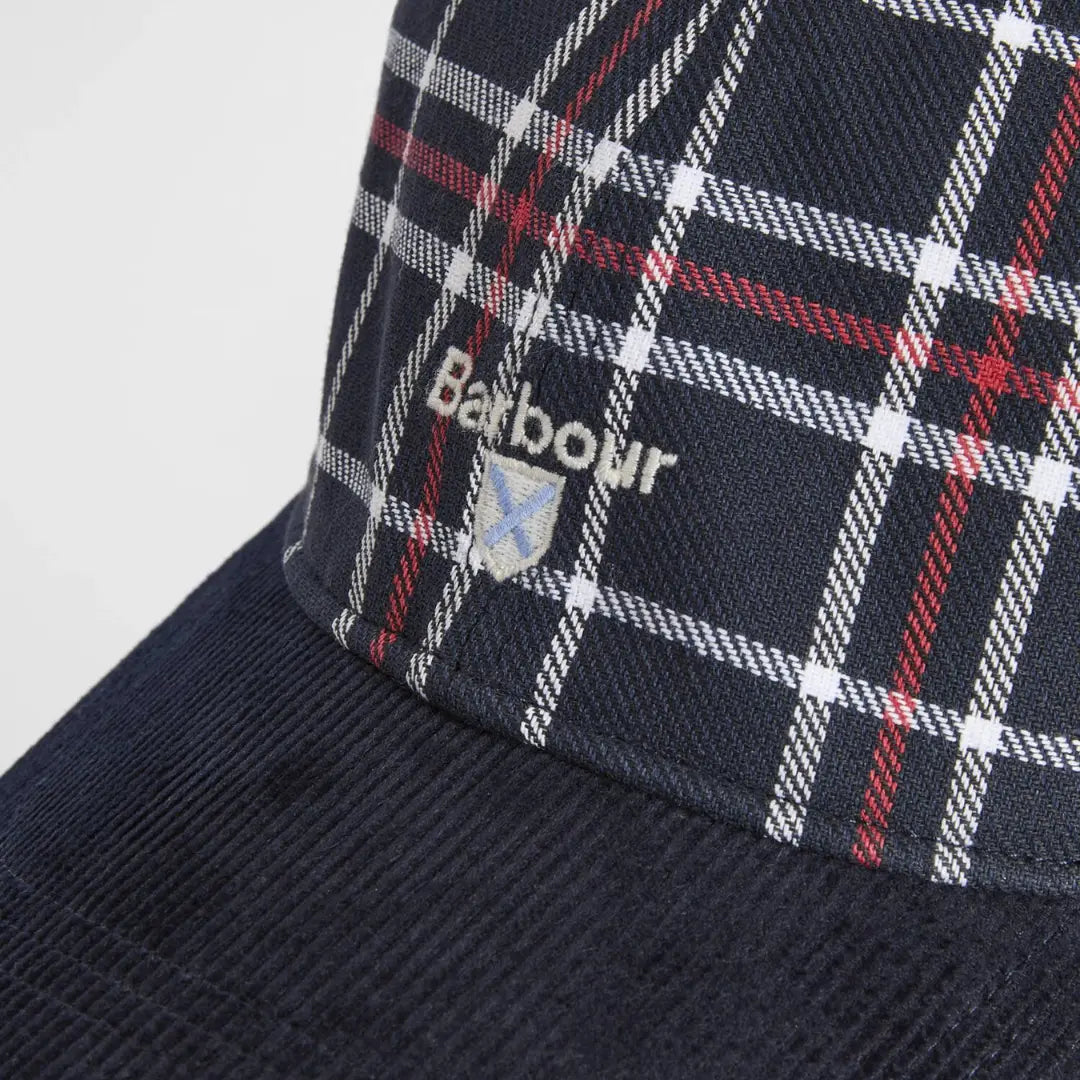 Macro du logo blanc brodé et de l'écusson bleu ciel sur le tartan Bleu Marine