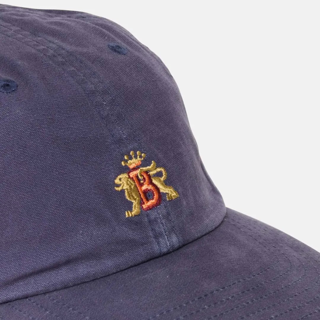 Macro sur le coton délavé bleu marine et la broderie du blason B aux deux lions dorés
