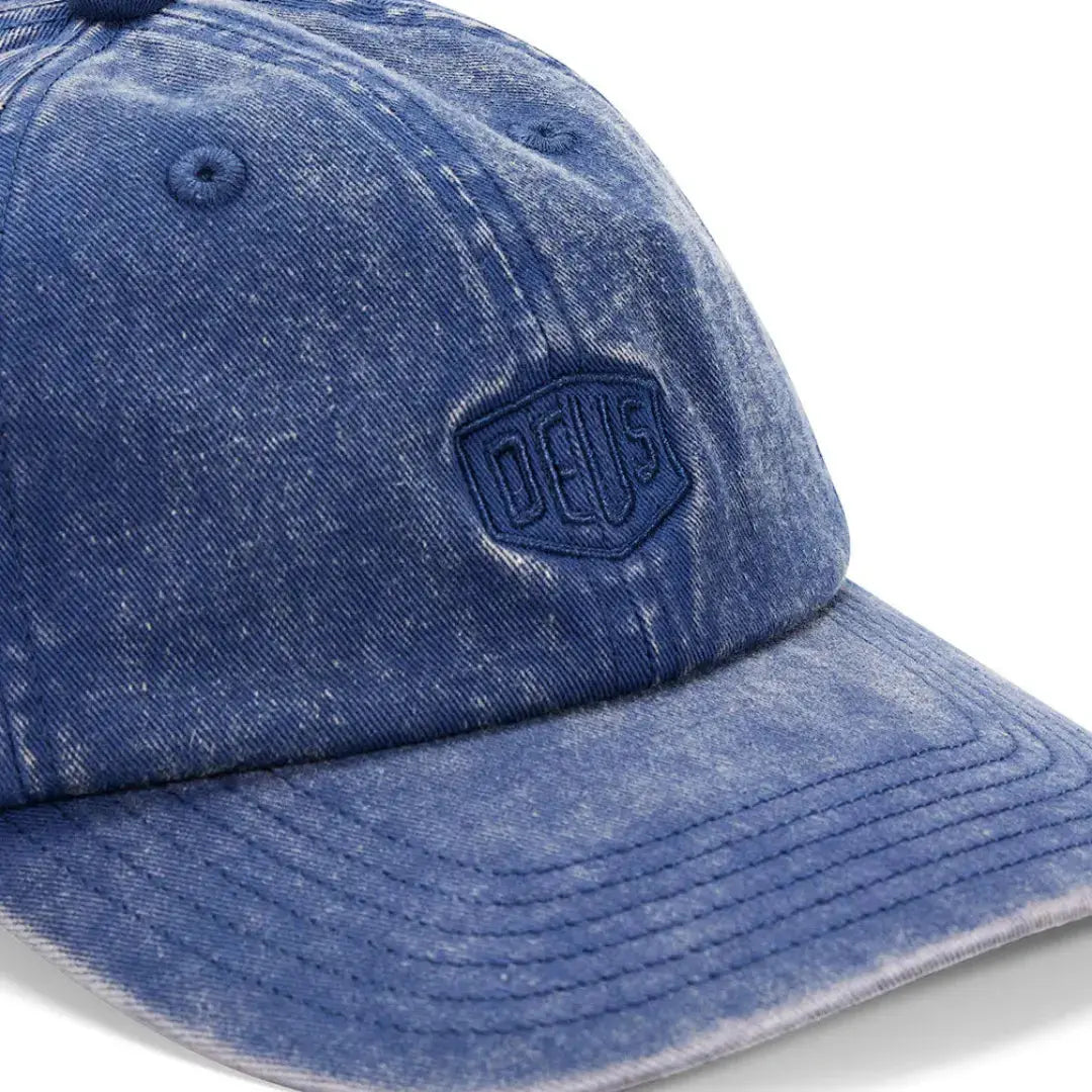 Macro du délavage acid wash bleu indigo et du bouclier brodé de la casquette Mechanic Blue