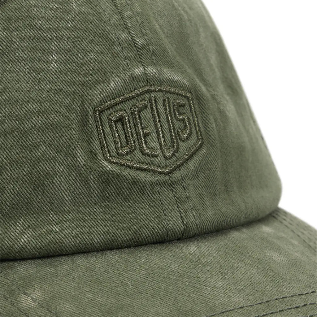 Gros plan du bouclier brodé vert olive sur la casquette Garment Dyed Cypress délavée