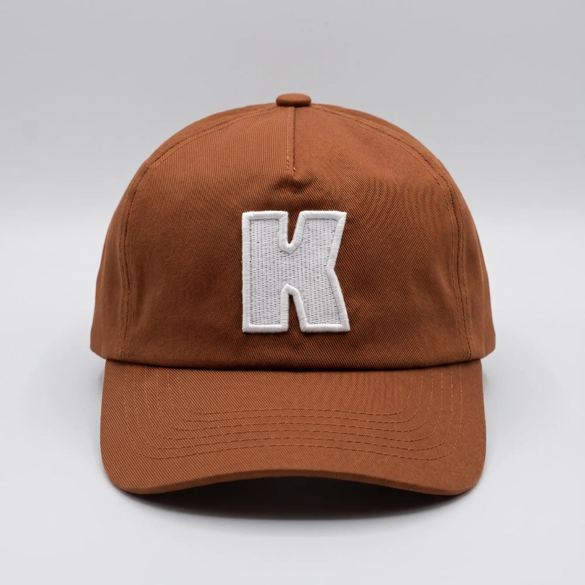 Casquette Klubb marron, vue de face avec le K blanc brodé en relief sur le panneau avant